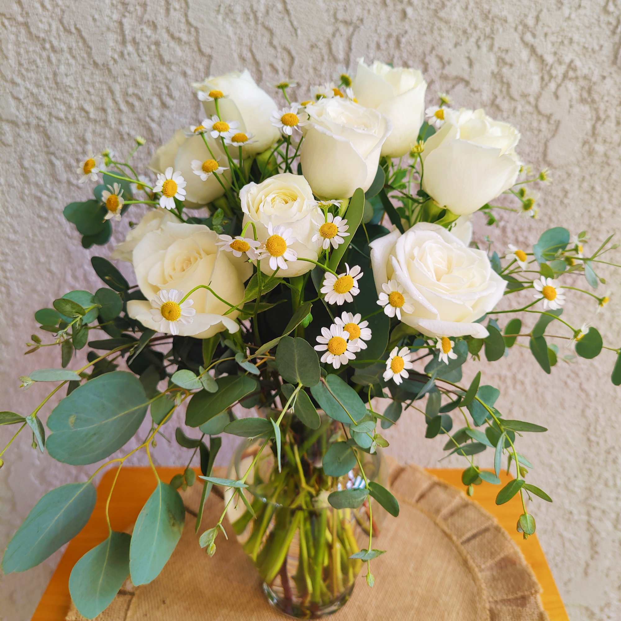White roses and small daisies in a glass vase