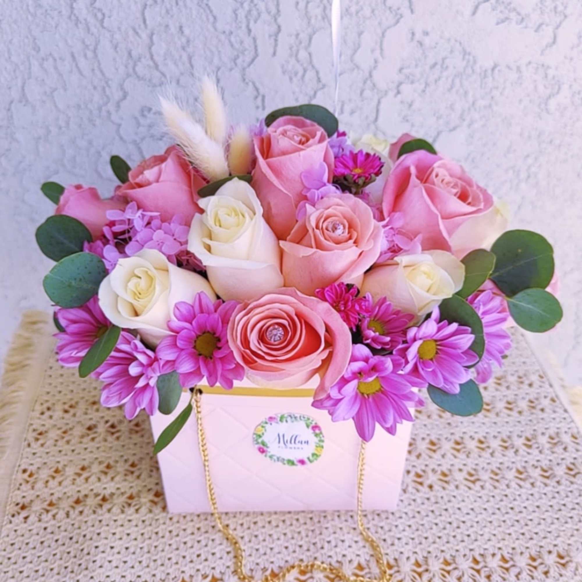 Pink and white roses with purple daisies in a white gift box