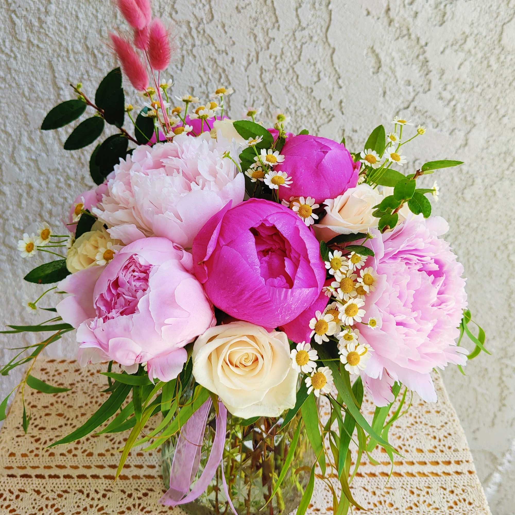 Pink and cream bouquet in a glass vase with small white daisies