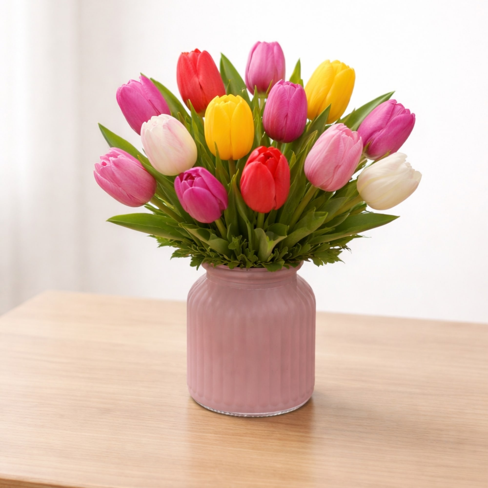 Colorful tulips arranged in a pink vase on a wooden table