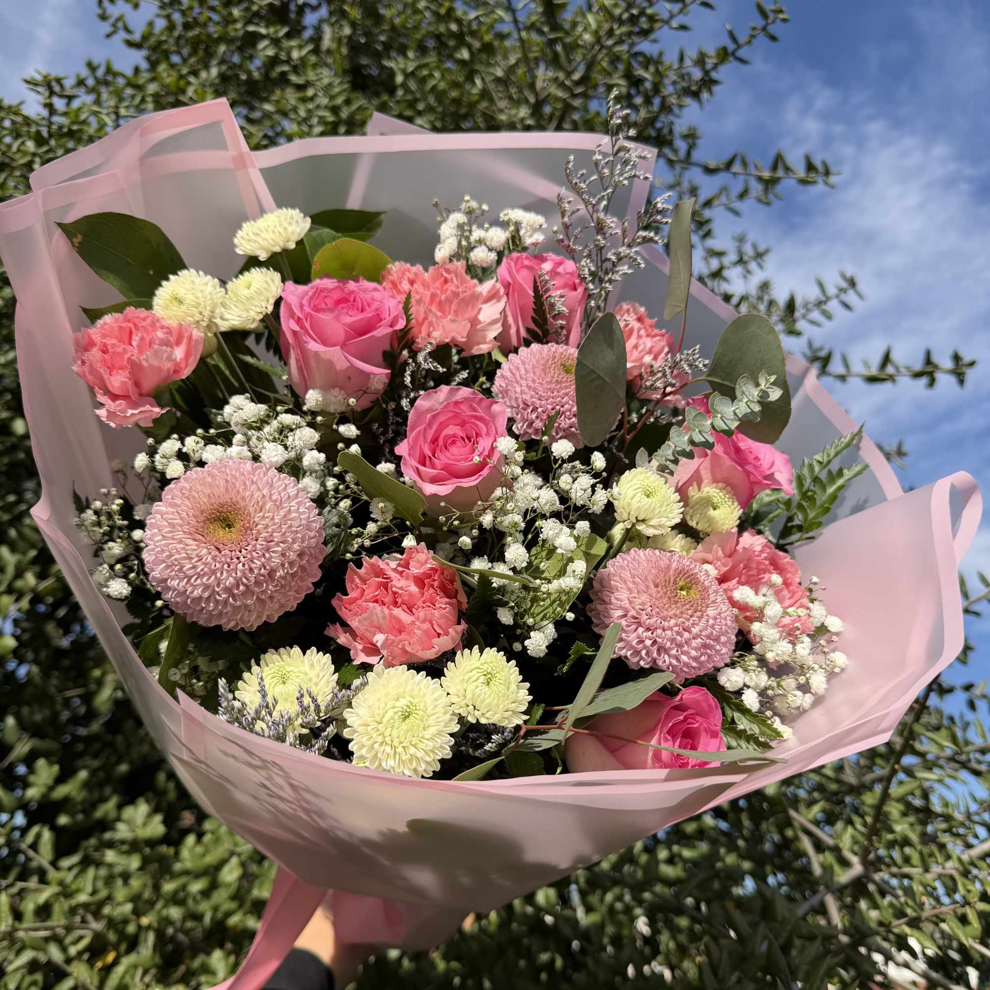 Pink bouquet with roses, carnations, and chrysanthemums wrapped in pale pink paper