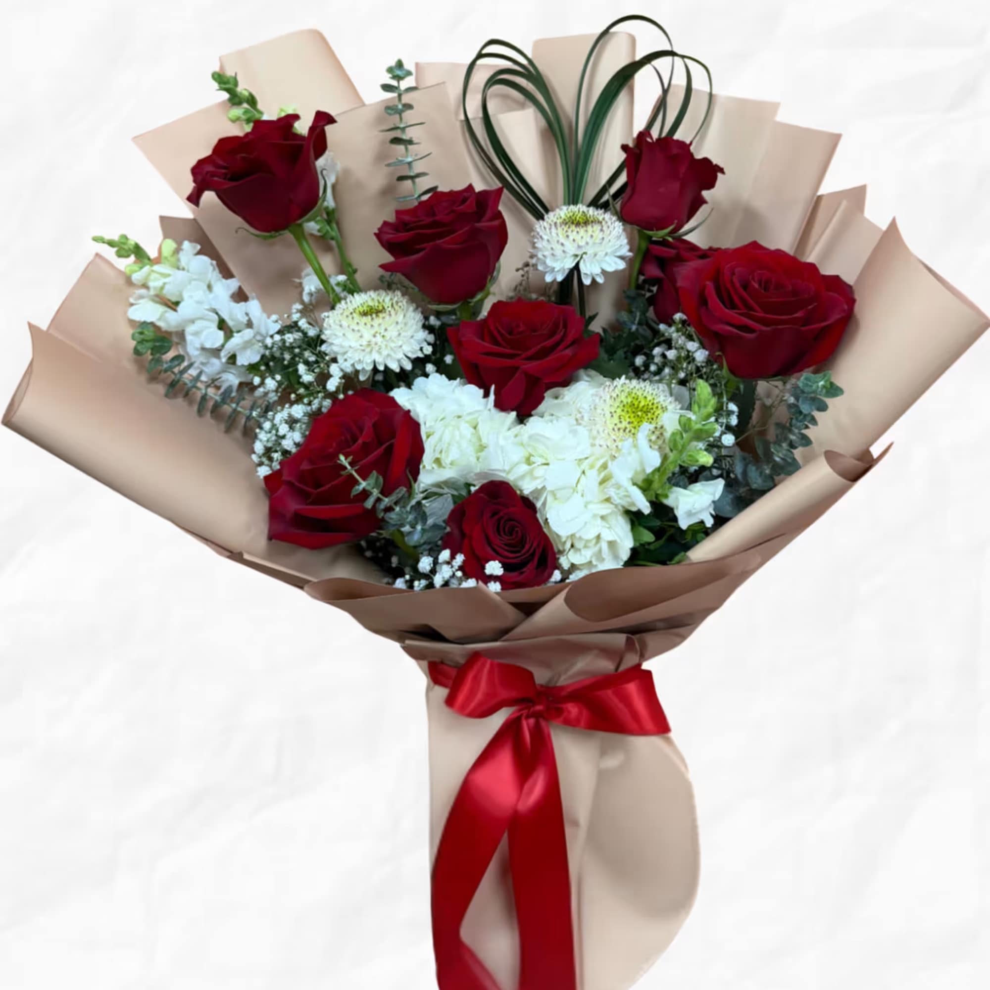 Bouquet of red roses and white flowers wrapped in beige paper with a red ribbon