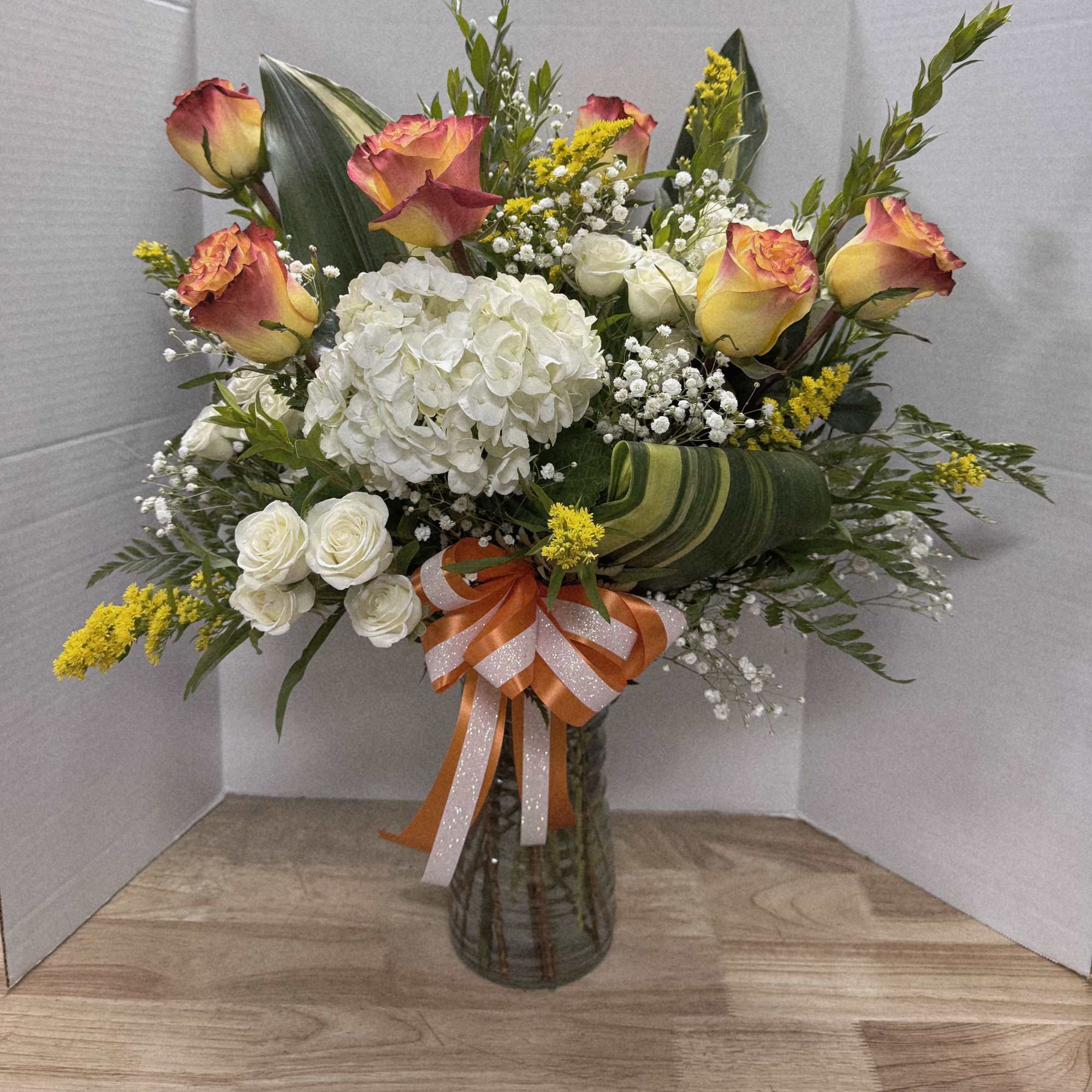Bouquet of roses, hydrangea, and white filler flowers in a glass vase