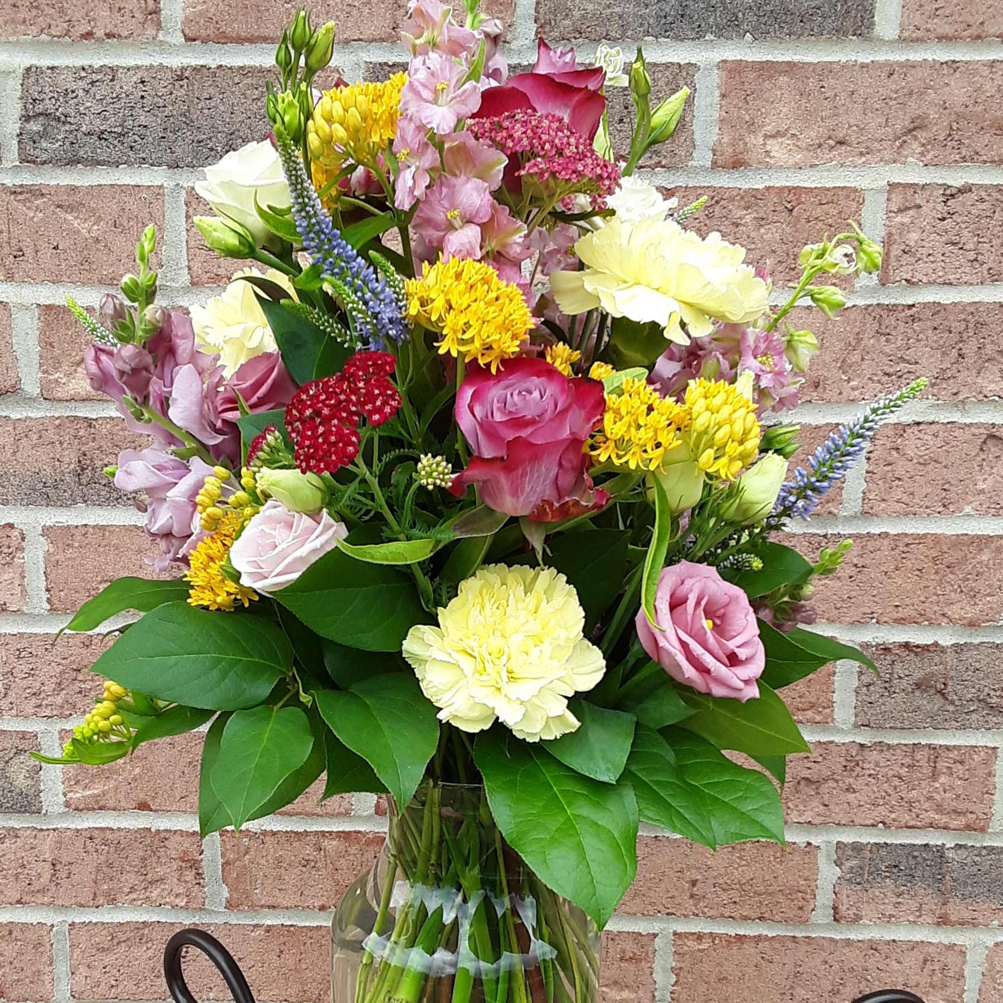 Mixed bouquet in a glass vase with pink, yellow, and white flowers