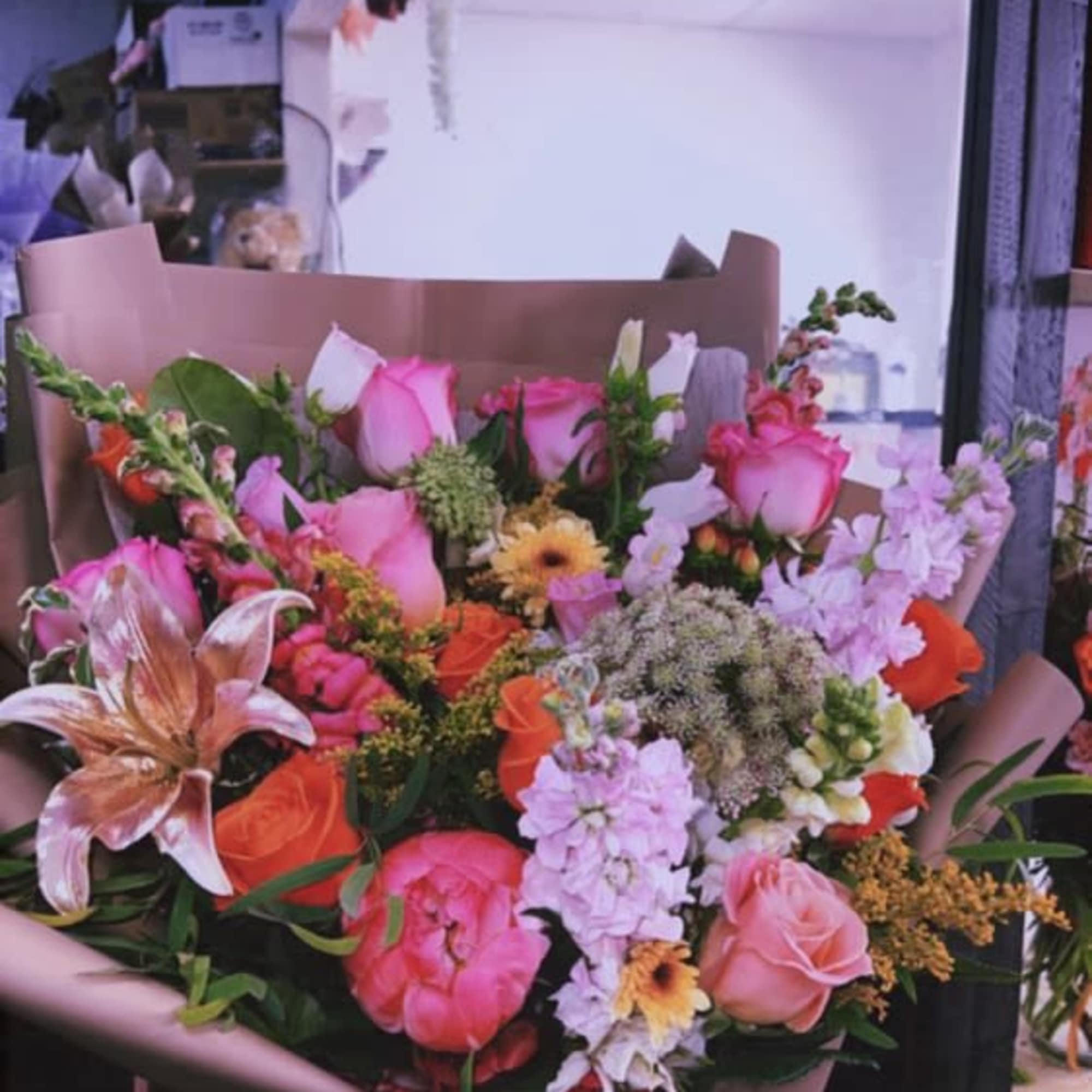 Large bouquet of pink and orange flowers wrapped in mauve paper