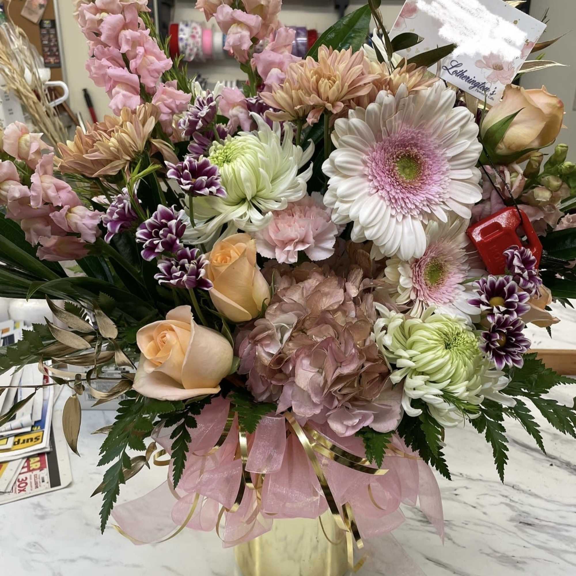 Mixed pastel bouquet in a gold vase with roses, gerbera daisies, and chrysanthemums