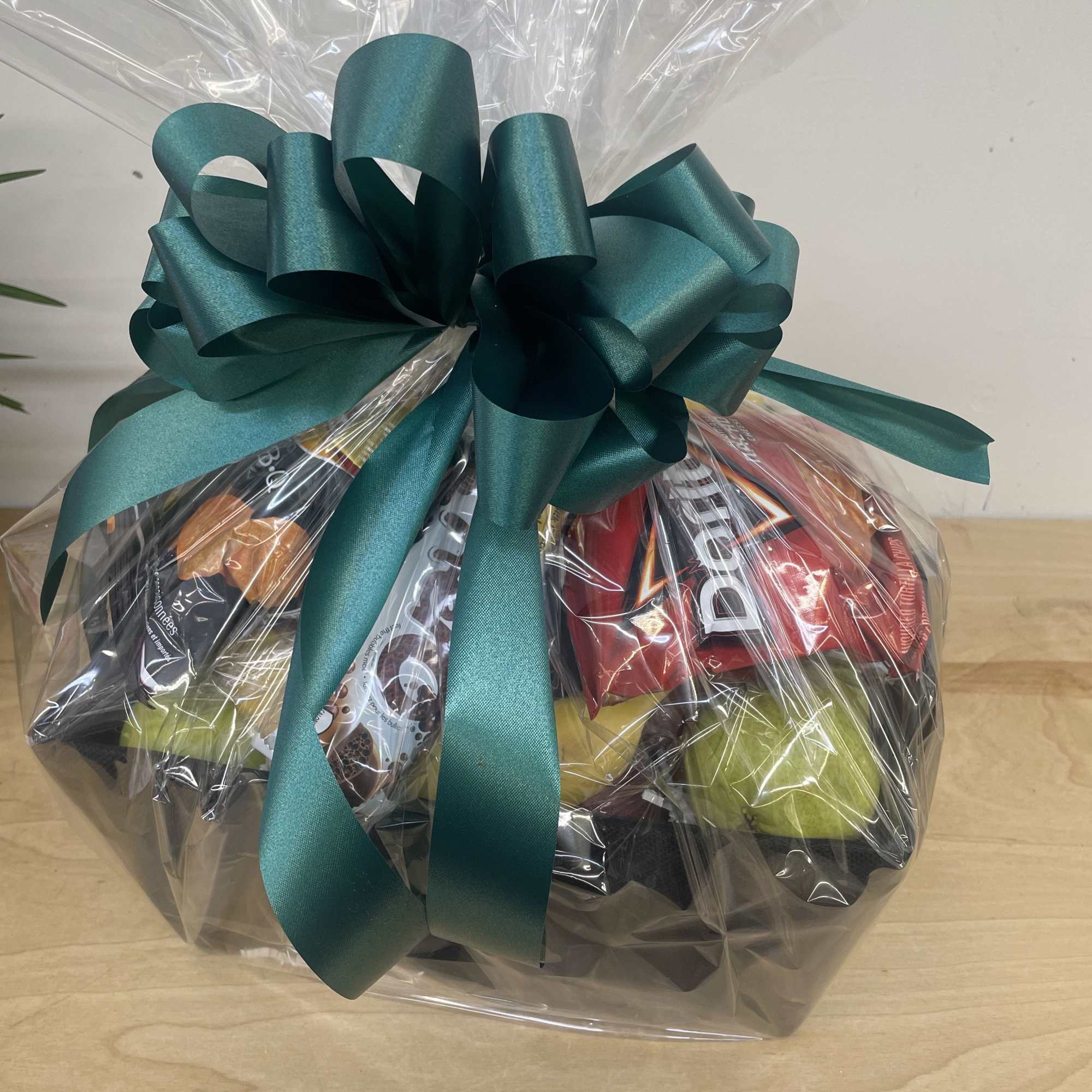 Gift basket wrapped in clear cellophane with a teal bow