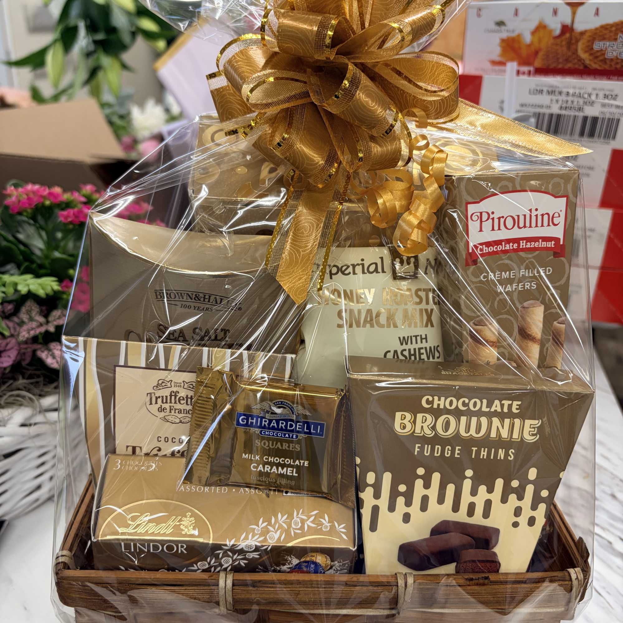 Gift basket of assorted chocolates and snack mixes wrapped with a gold bow