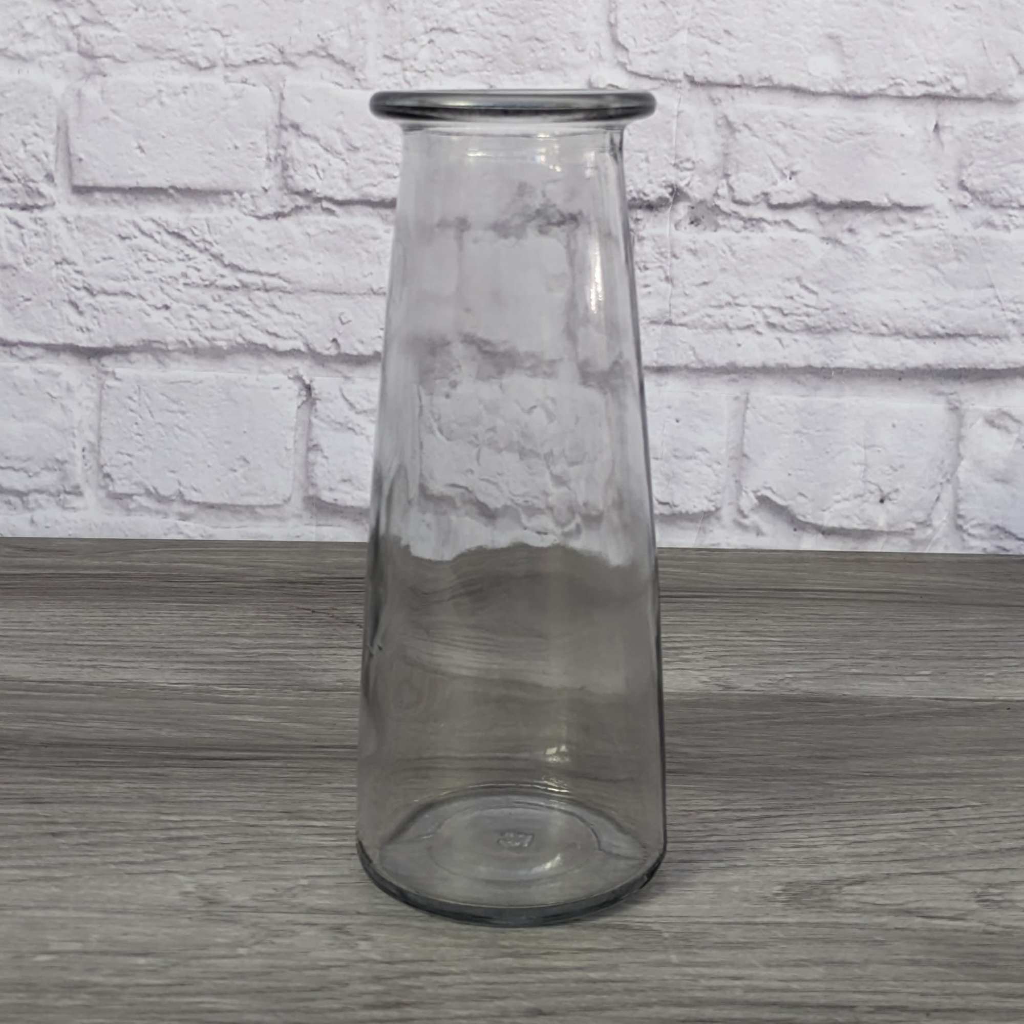 Clear tapered glass vase on a wooden surface