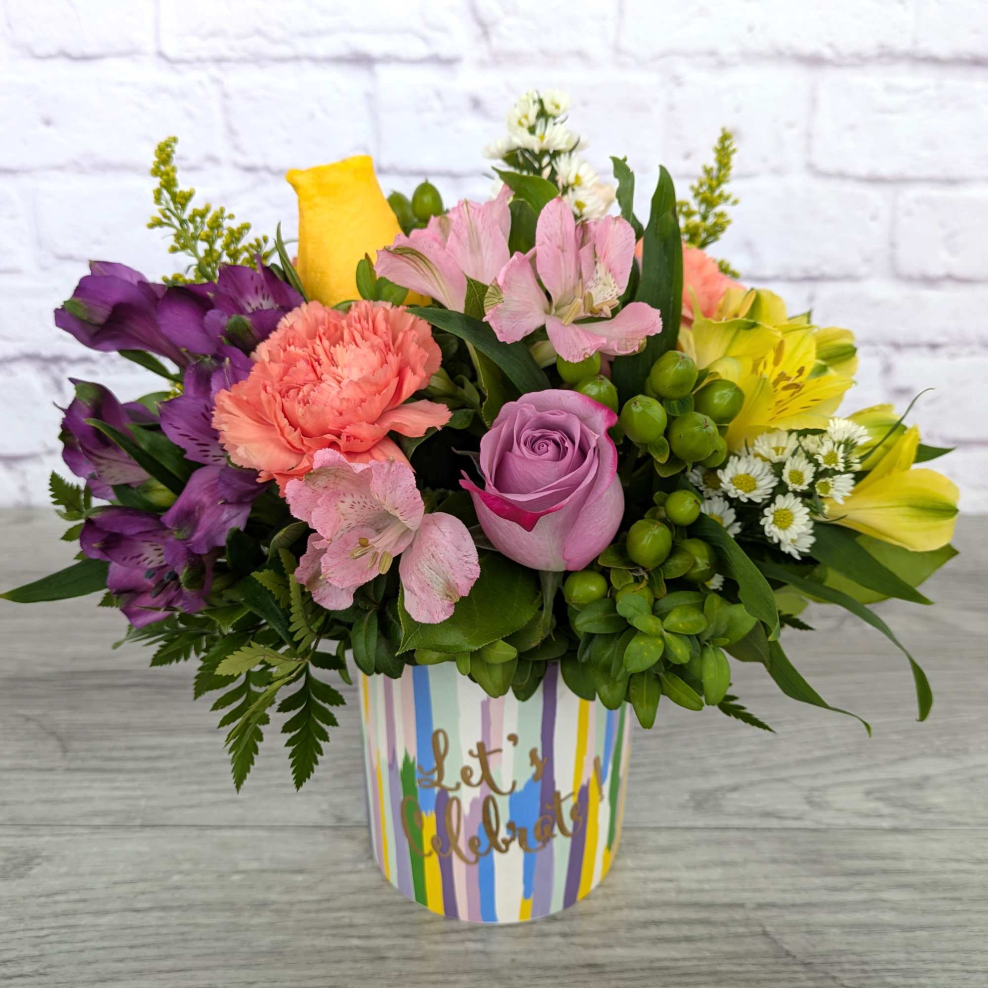 Colorful mixed flower arrangement in a striped container