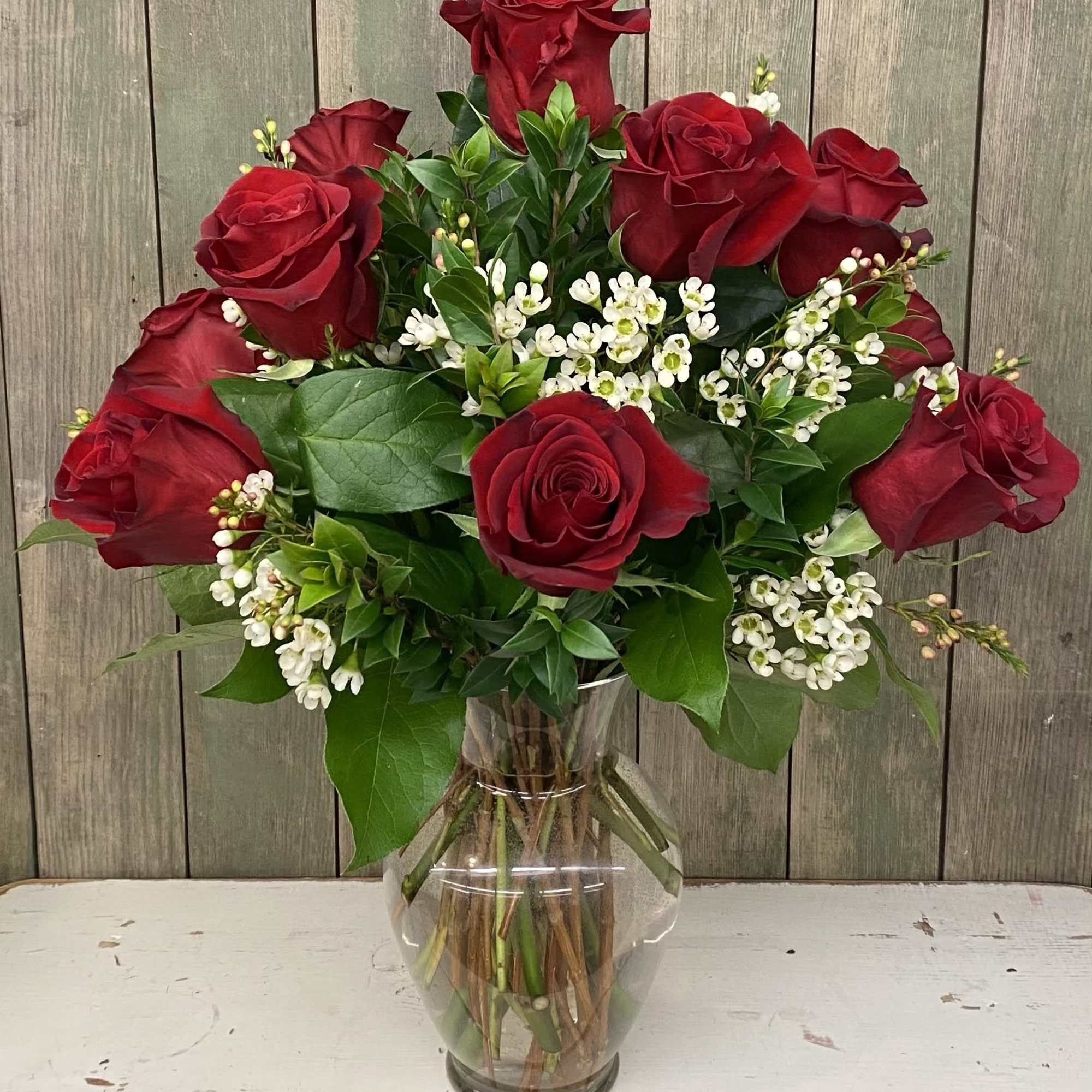 Red roses and white filler flowers arranged in a clear glass vase