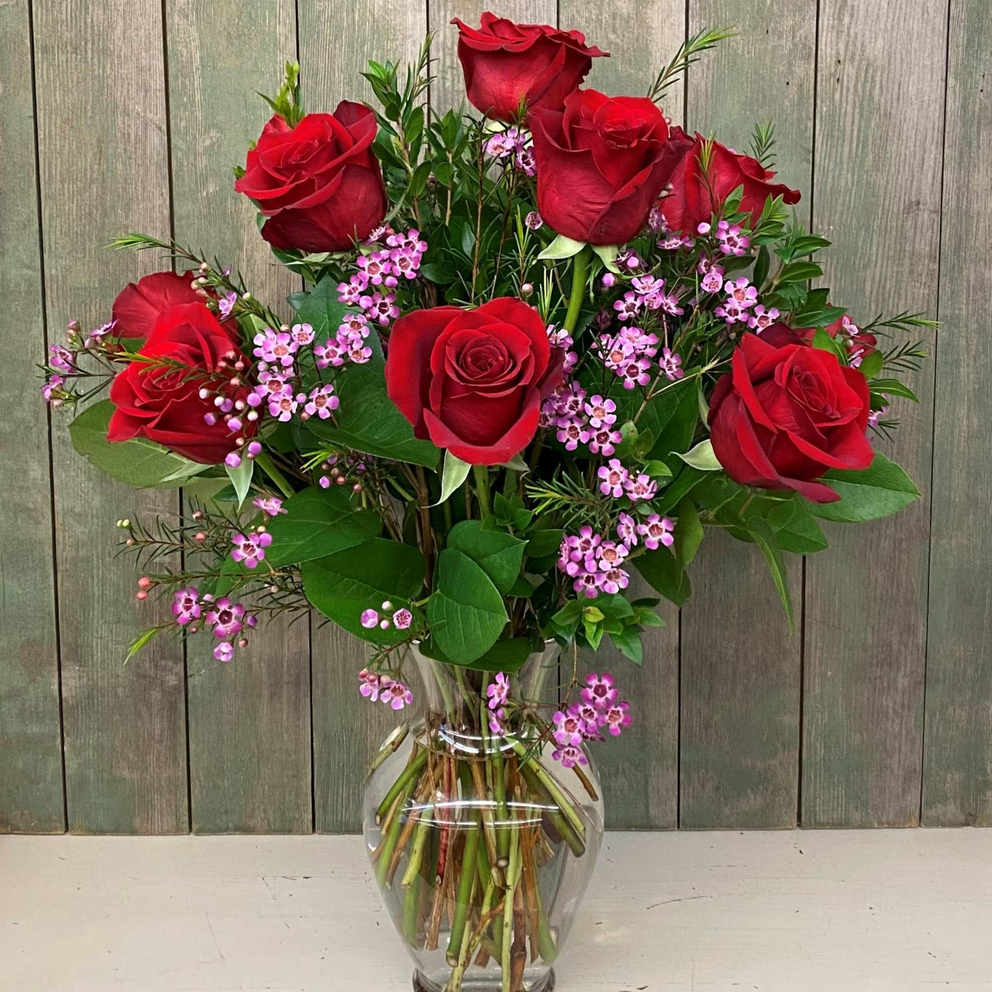 Red roses and pink filler flowers in a clear glass vase