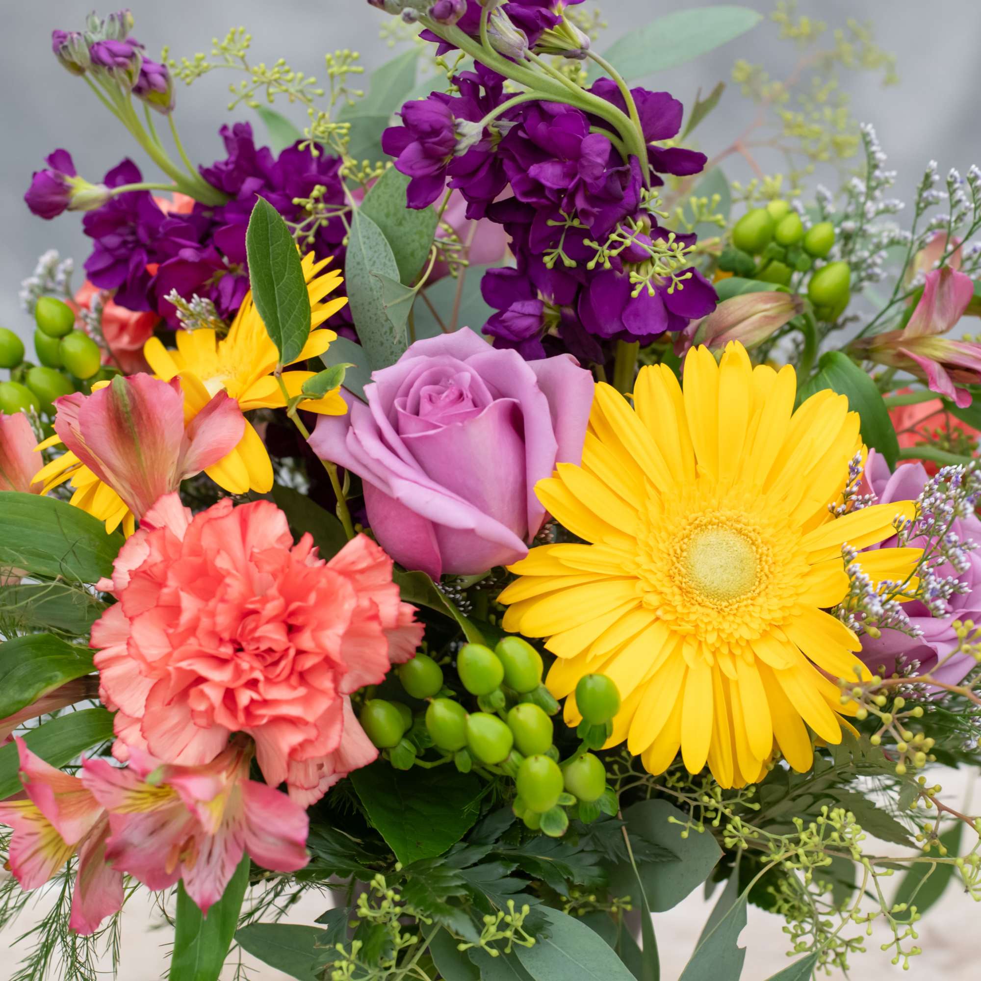 Mixed bouquet with purple roses, yellow daisies, and pink carnations