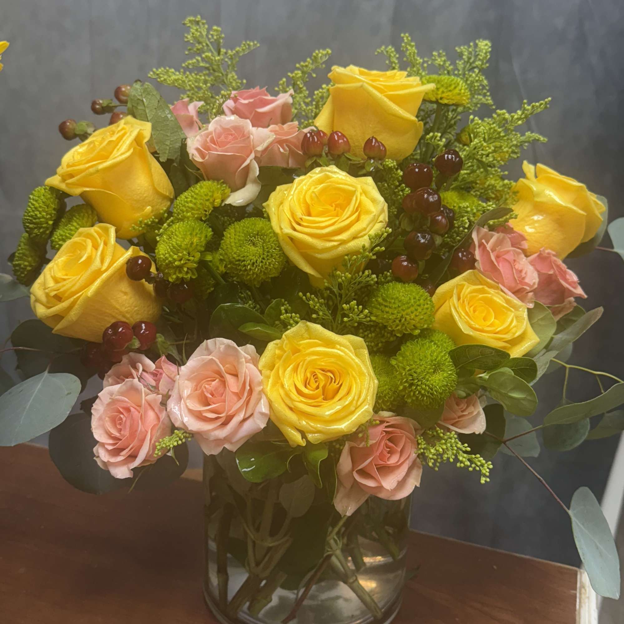 Yellow and pink roses arranged in a glass vase