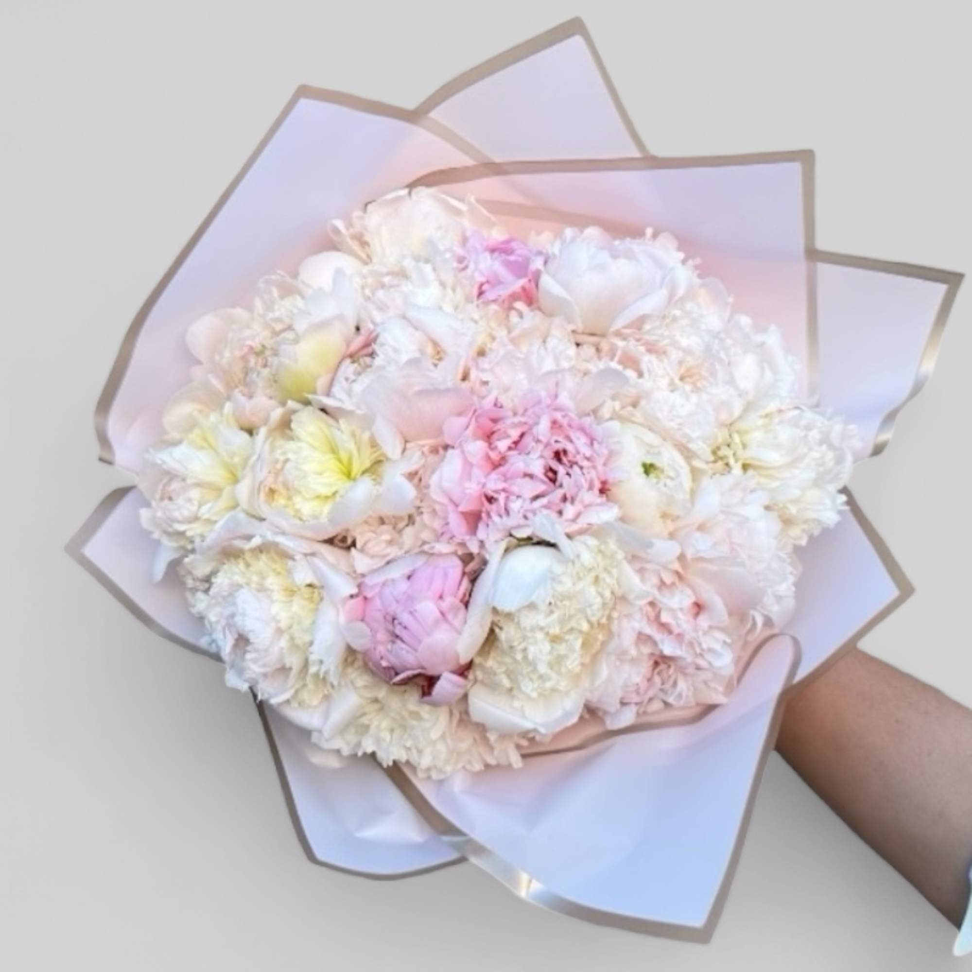 Pastel bouquet of white and pink flowers wrapped in pale paper