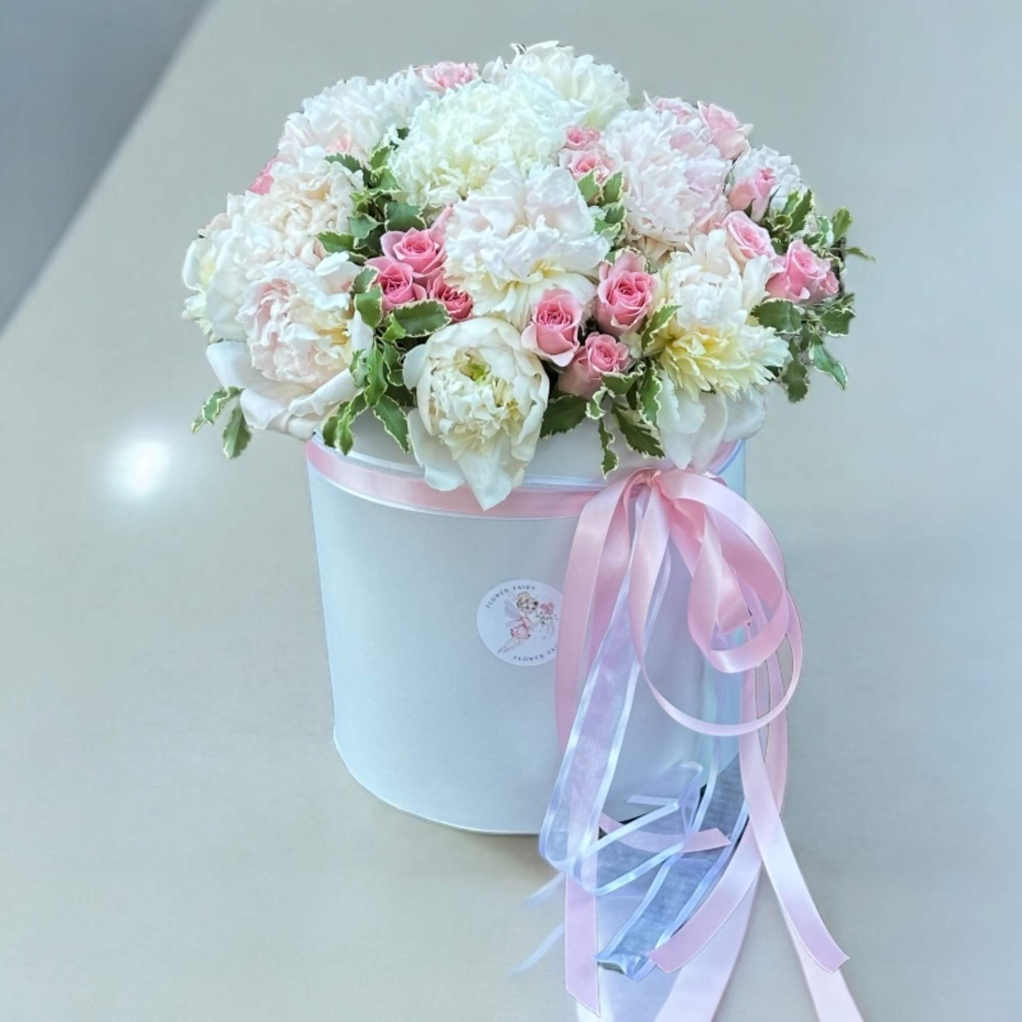 Pink and white floral arrangement in a white hat box with ribbon