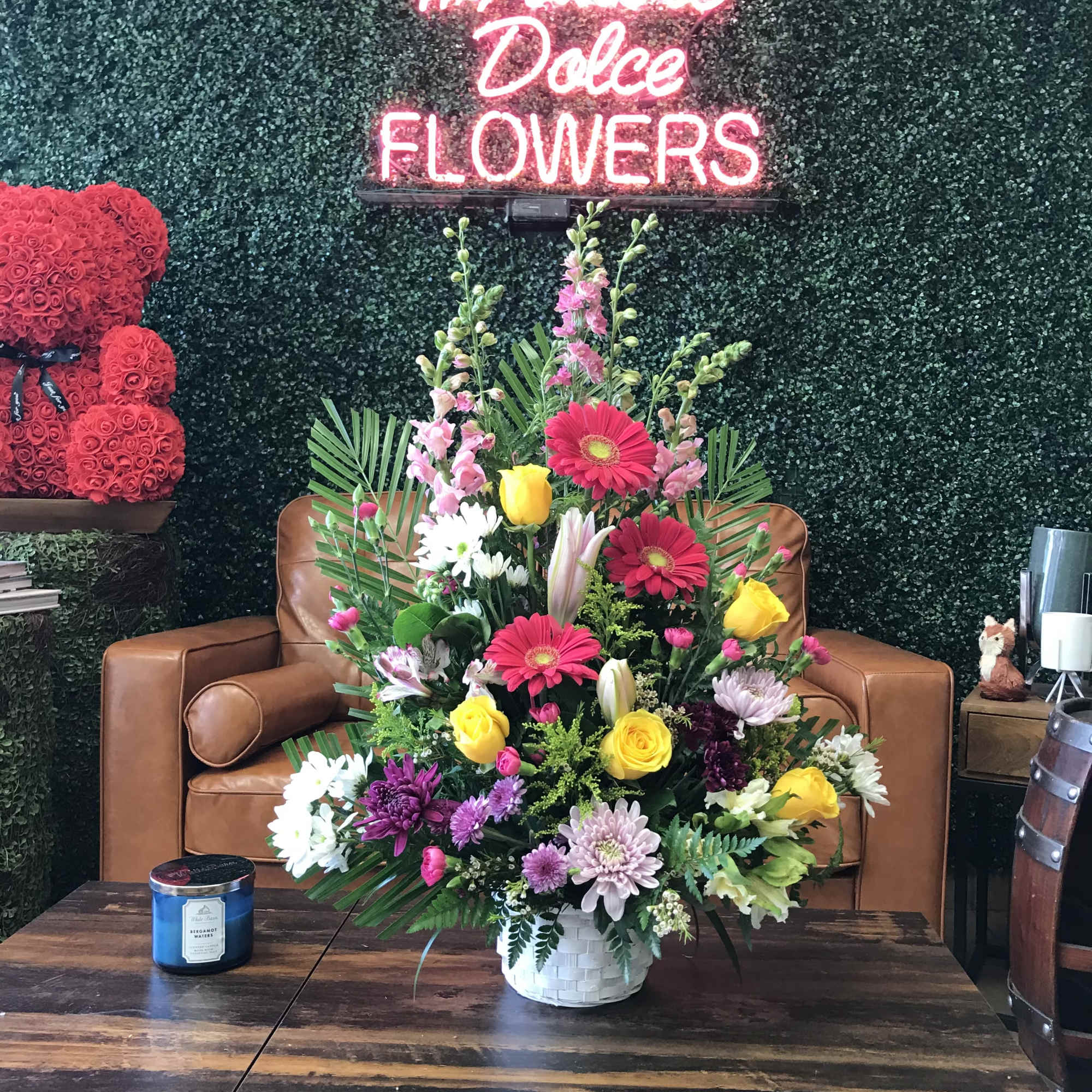 Mixed flower arrangement in a white basket on a table