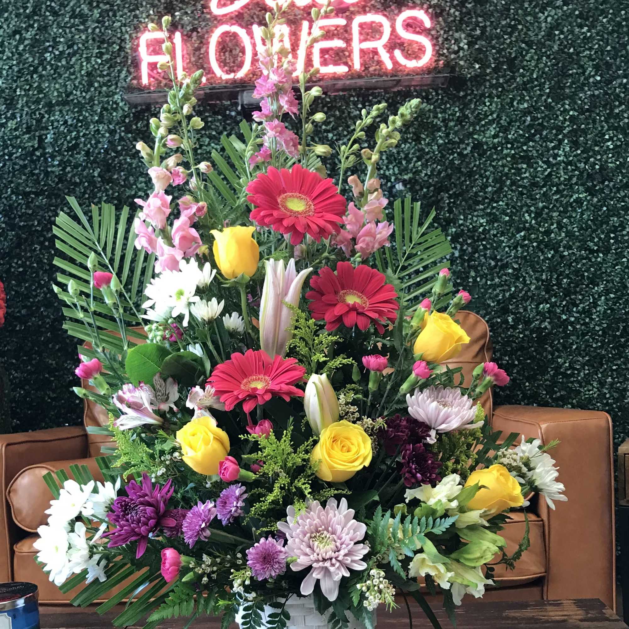 Large mixed flower arrangement in a white basket vase