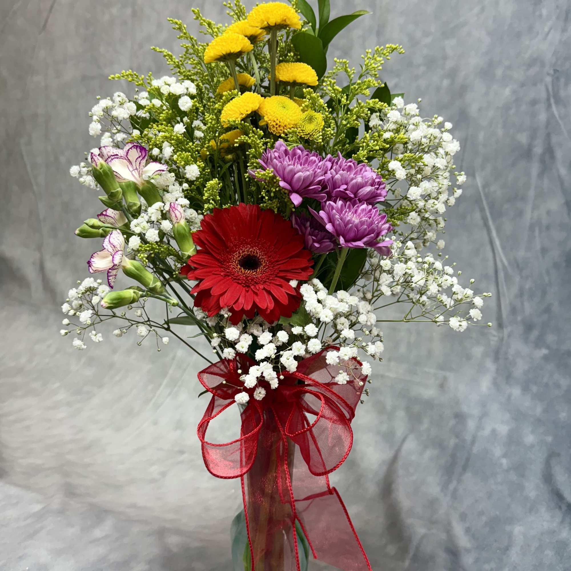 Mixed bouquet in a glass vase with red, purple, and yellow flowers