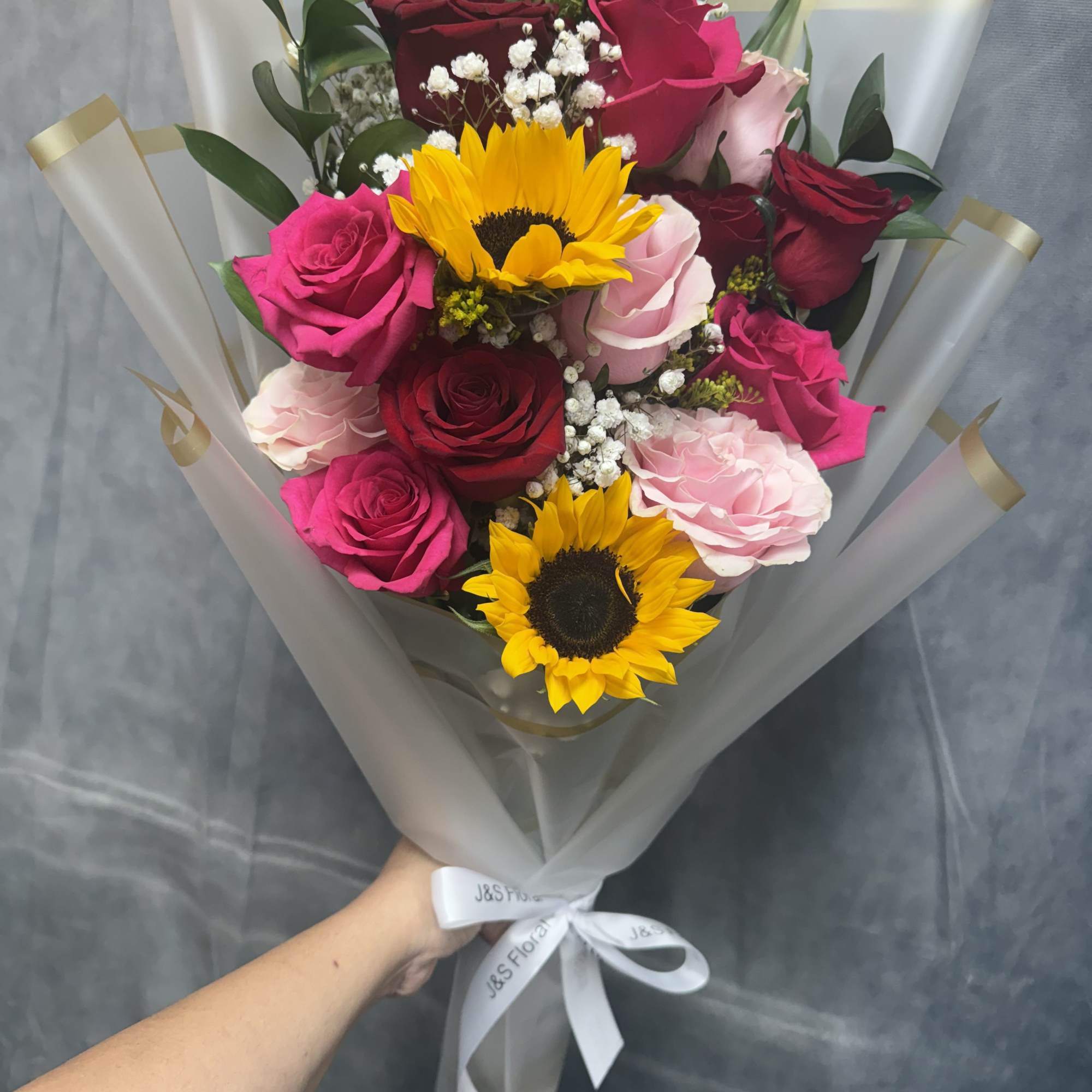 Bouquet of roses and sunflowers wrapped in translucent paper