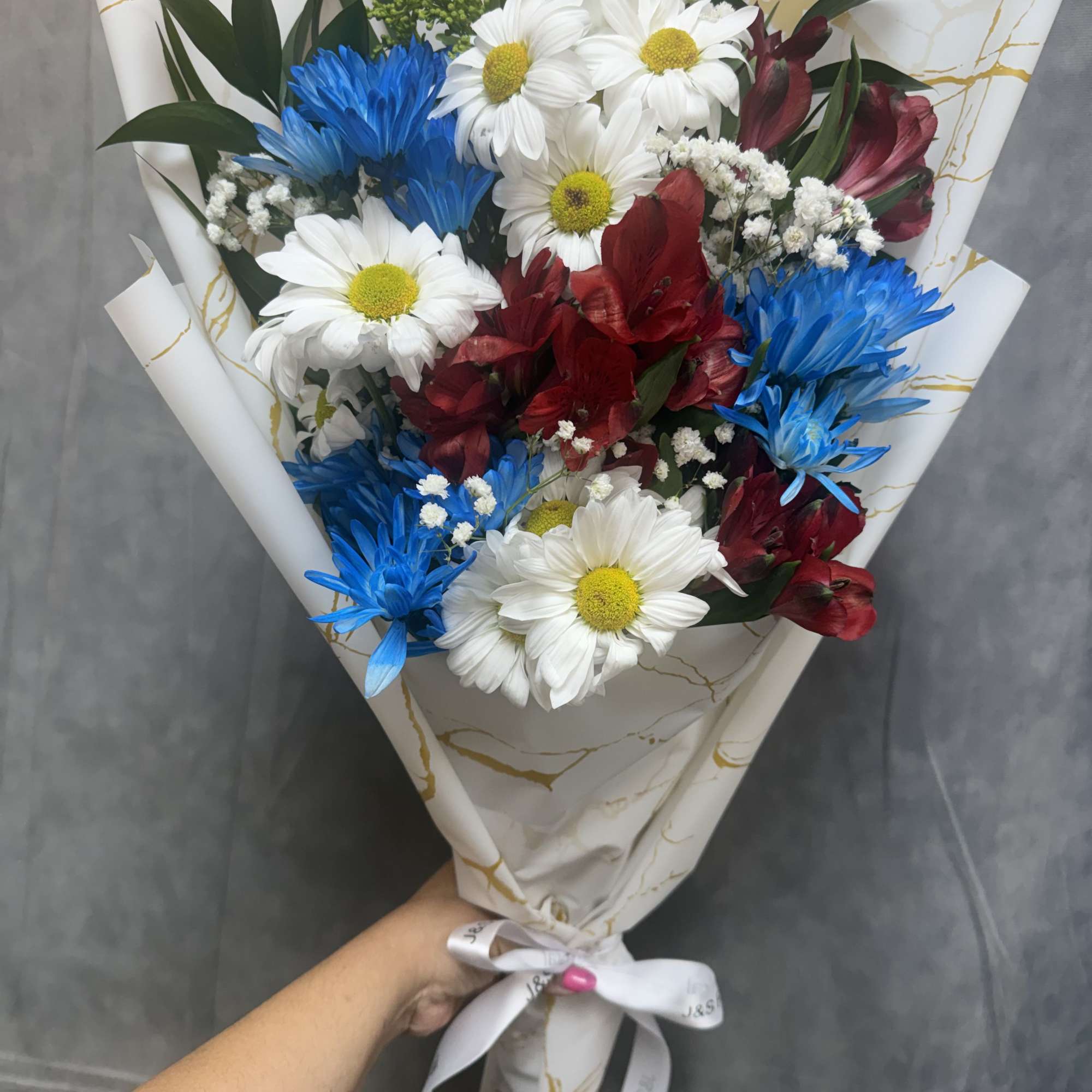 Red, white and blue alstroemeria, daisies and other flowers in a hand-tied