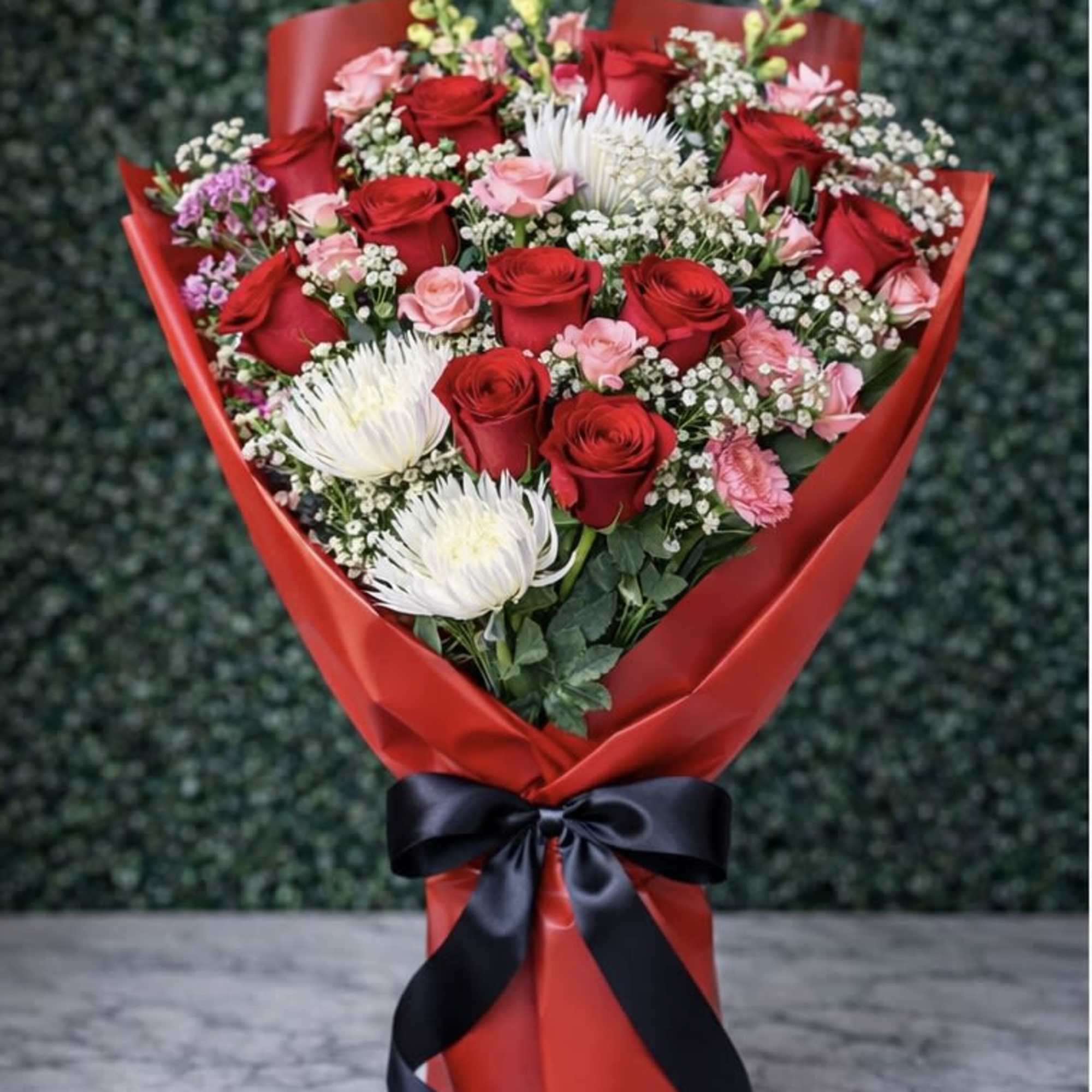 Bouquet of red and pink roses with white blooms wrapped in red paper