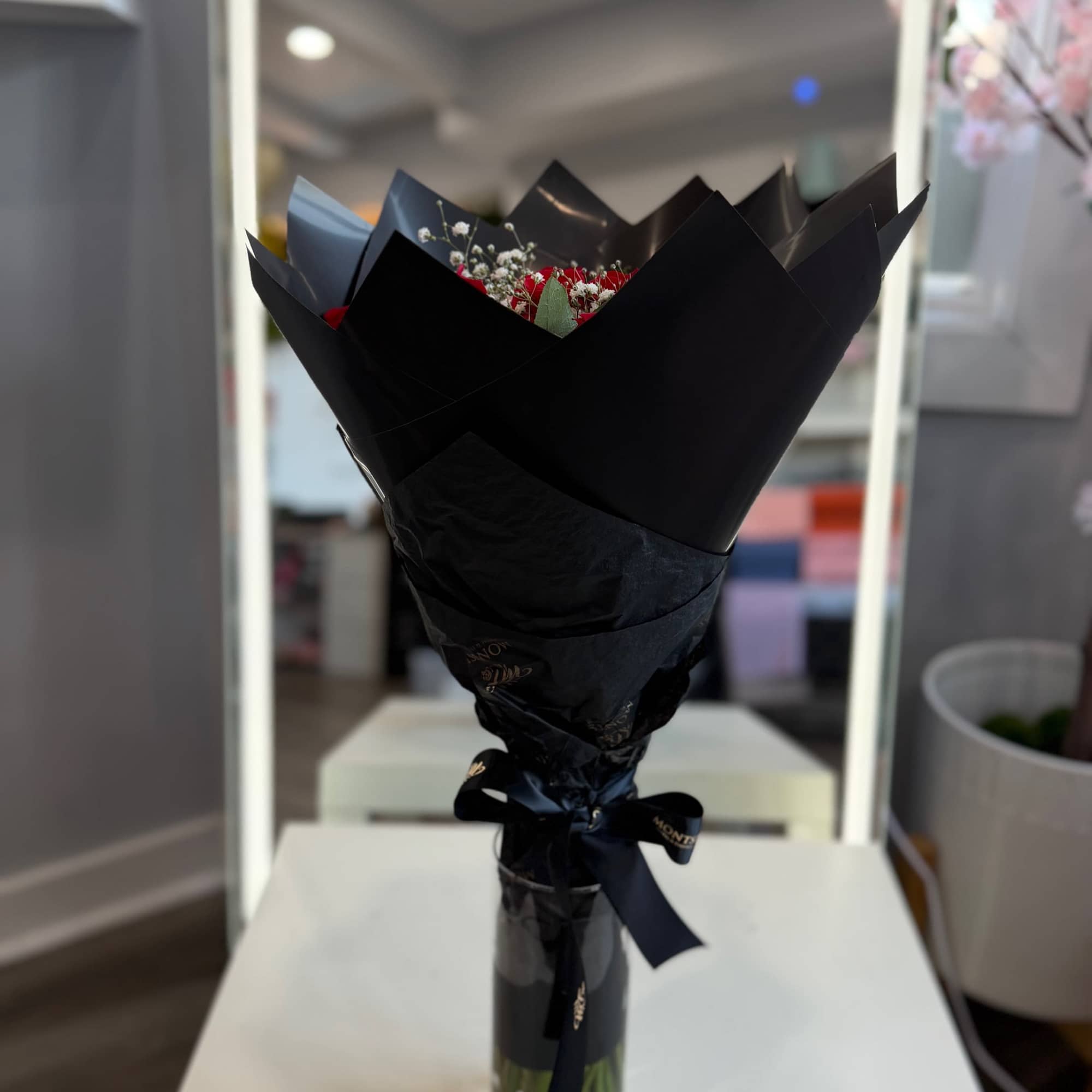 Bouquet of red flowers wrapped in black paper in a glass vase