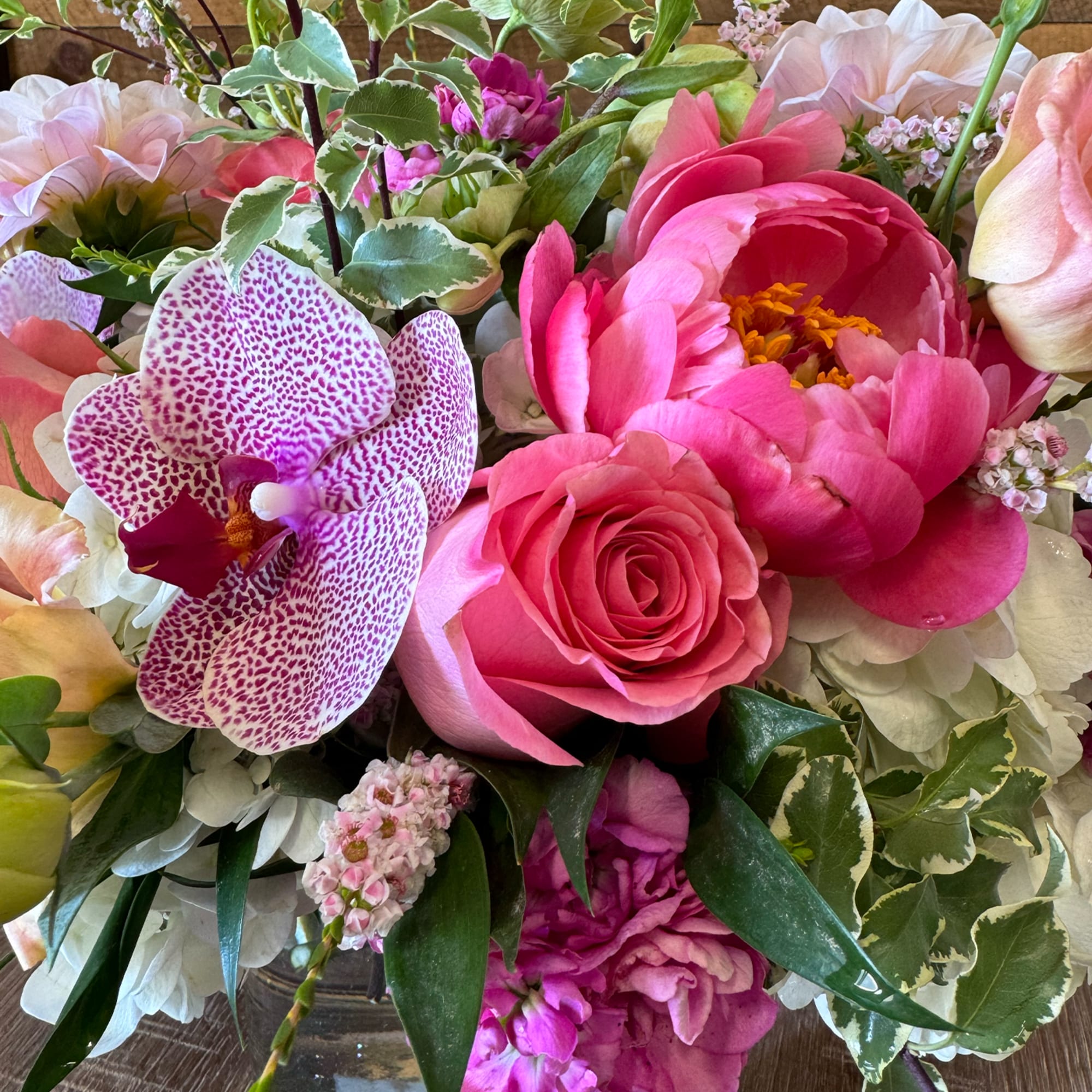 Pink peonies, a spotted orchid, and a pink rose in a vase