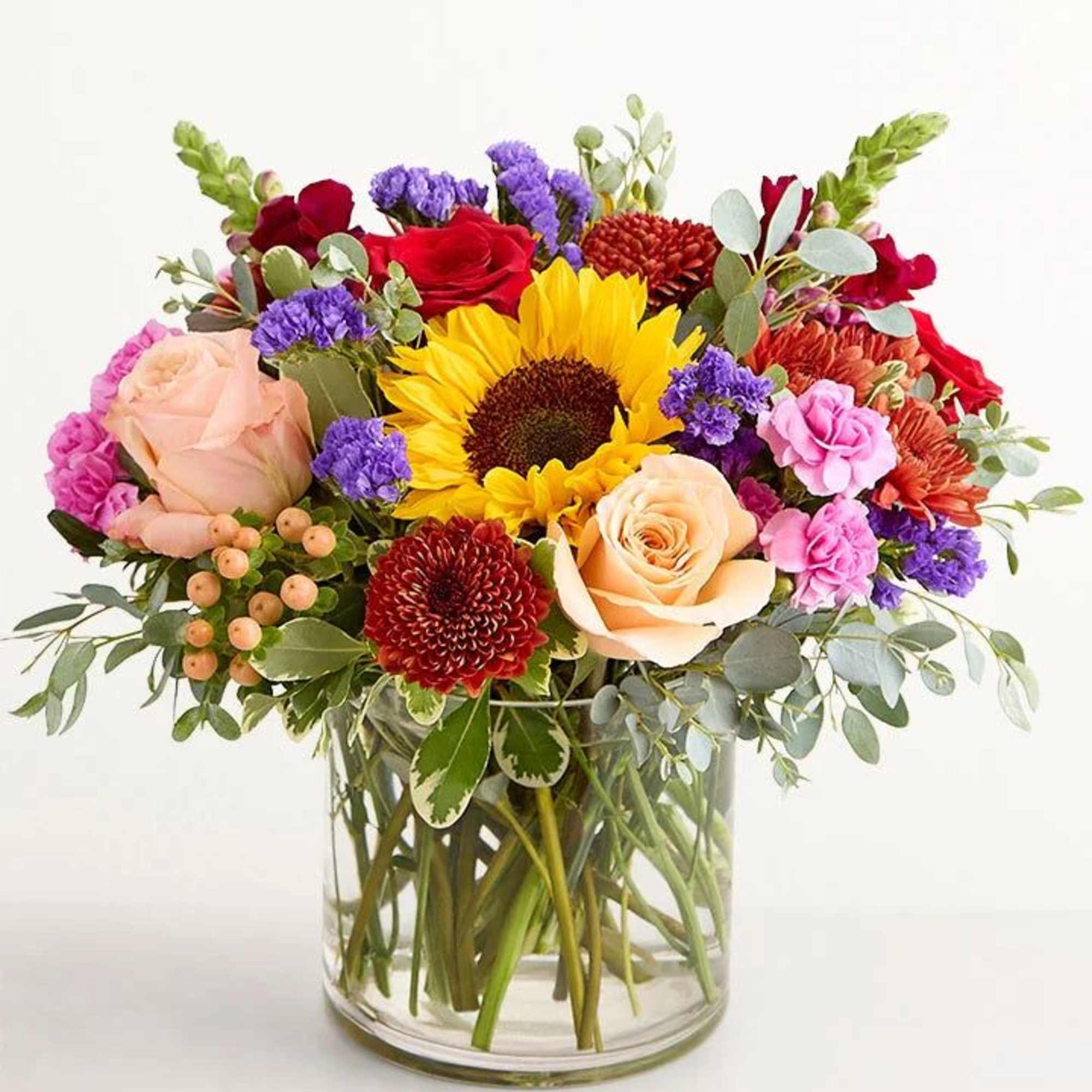 Mixed bouquet with sunflowers, roses, and chrysanthemums in a glass vase