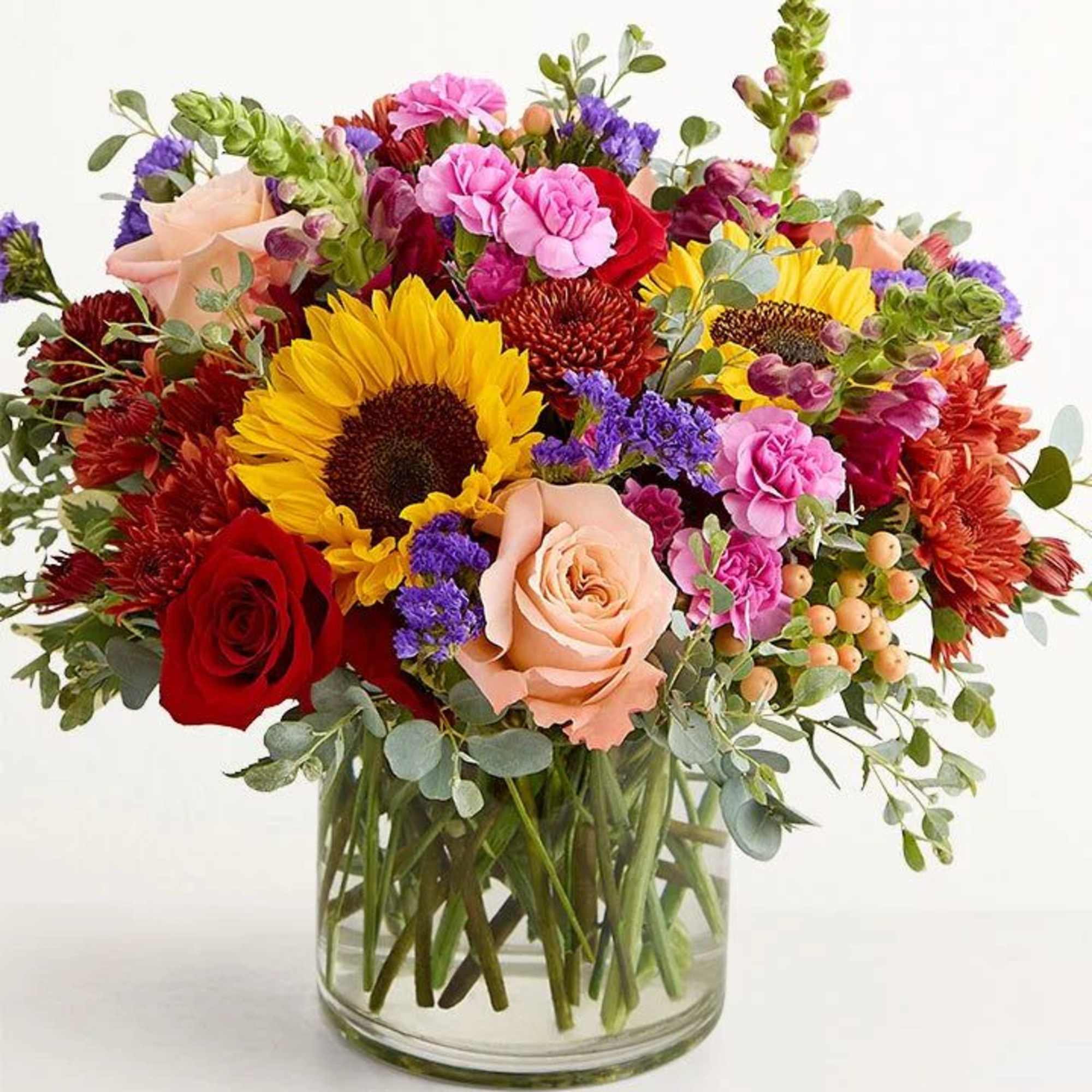 Mixed bouquet with sunflowers, roses, and chrysanthemums in a glass vase