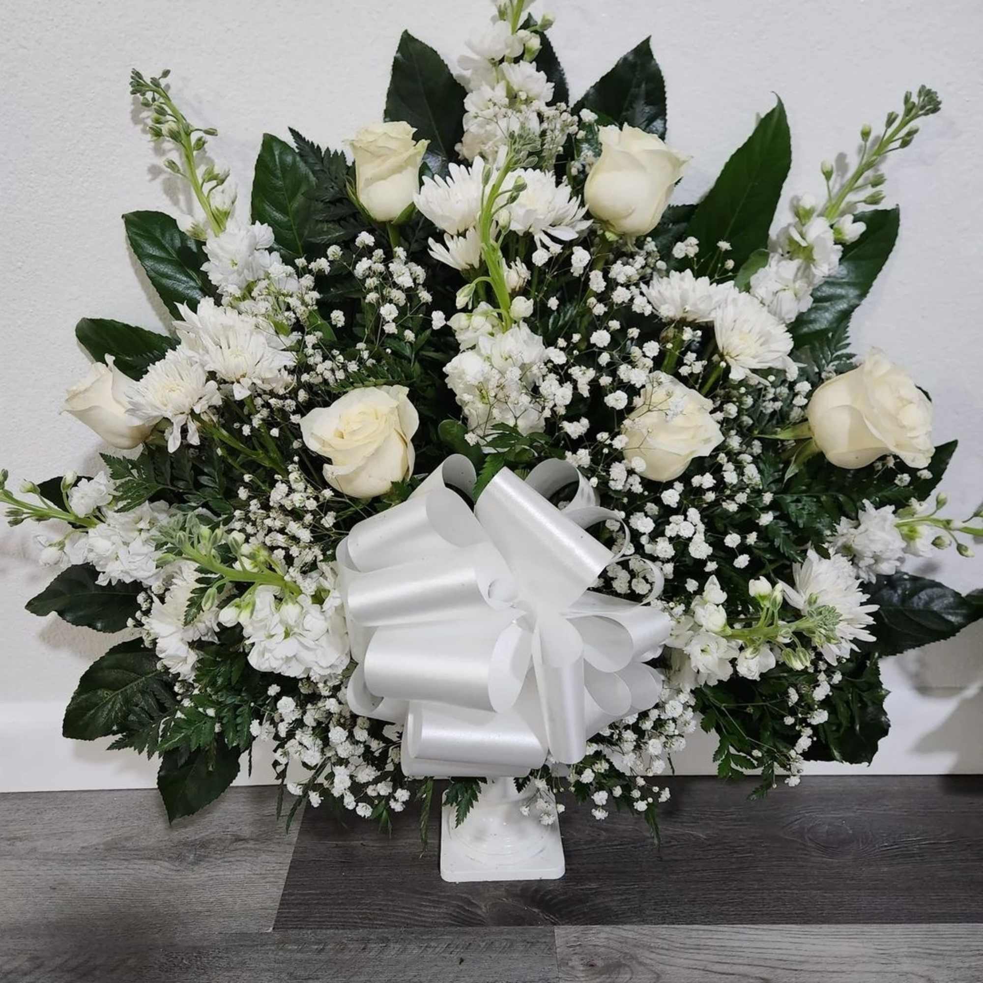 White rose and chrysanthemum arrangement with a large white bow