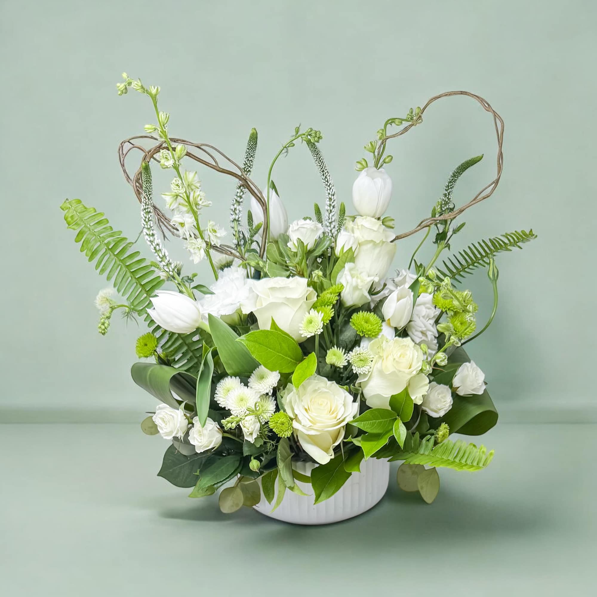 White floral arrangement in a white vase with looping twig accents
