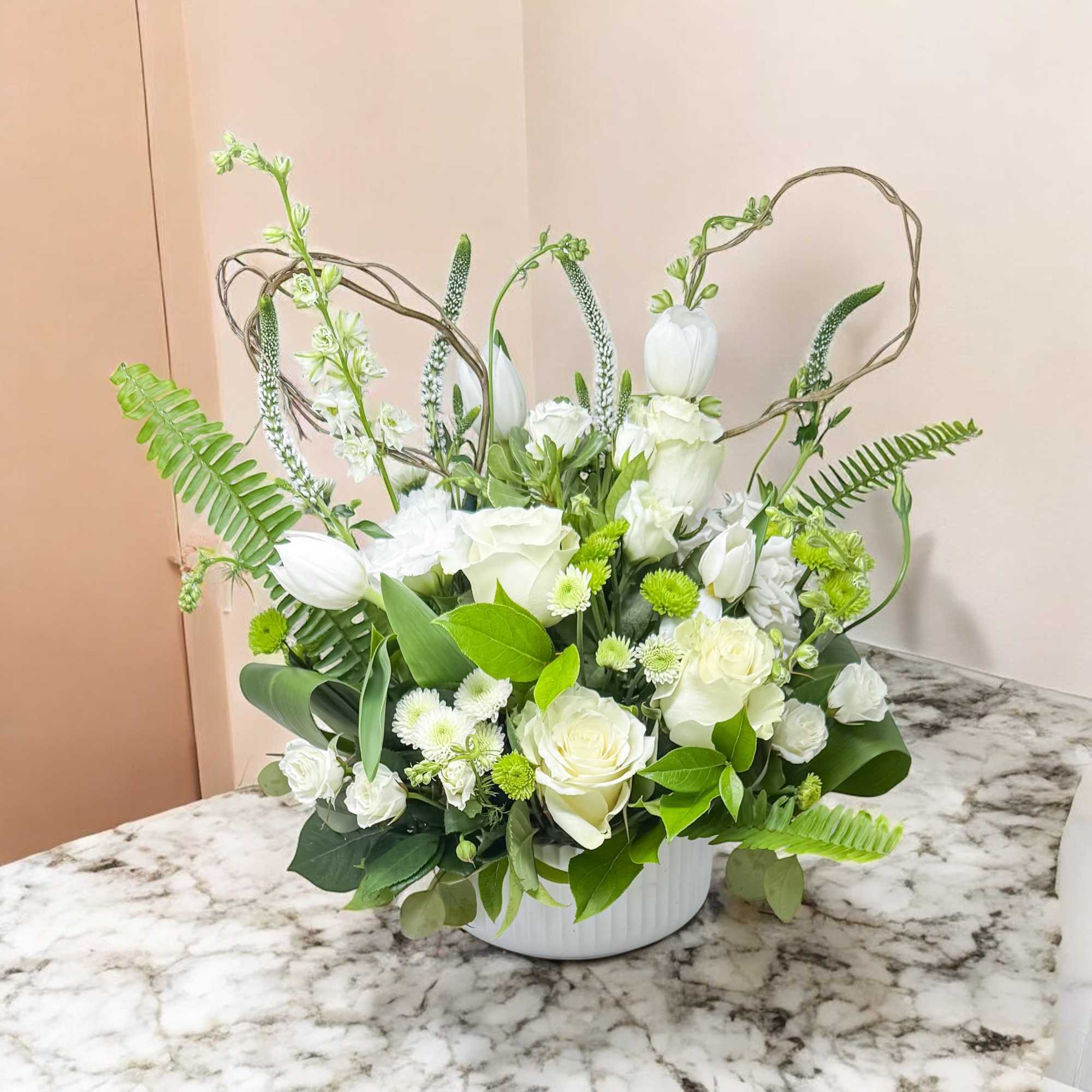 White floral arrangement in a white vase with green accents