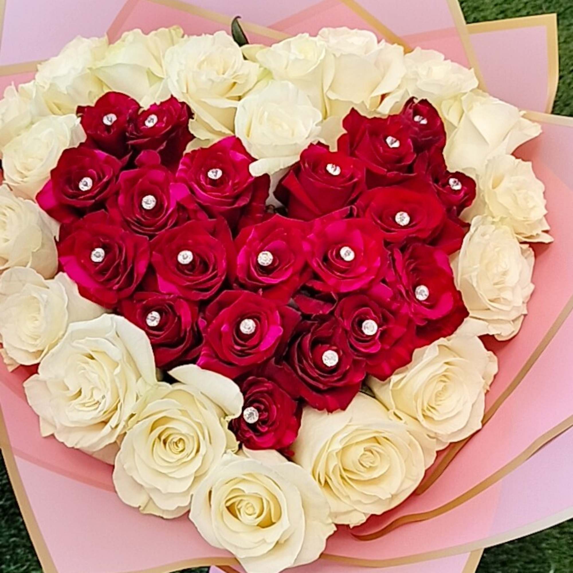 Heart-shaped bouquet of red and white roses wrapped in pink paper
