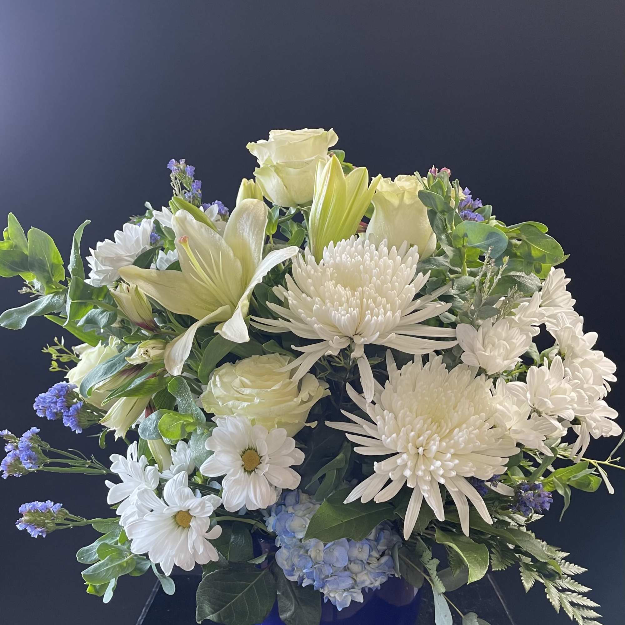 White flowers arranged in a blue vase with touches of purple