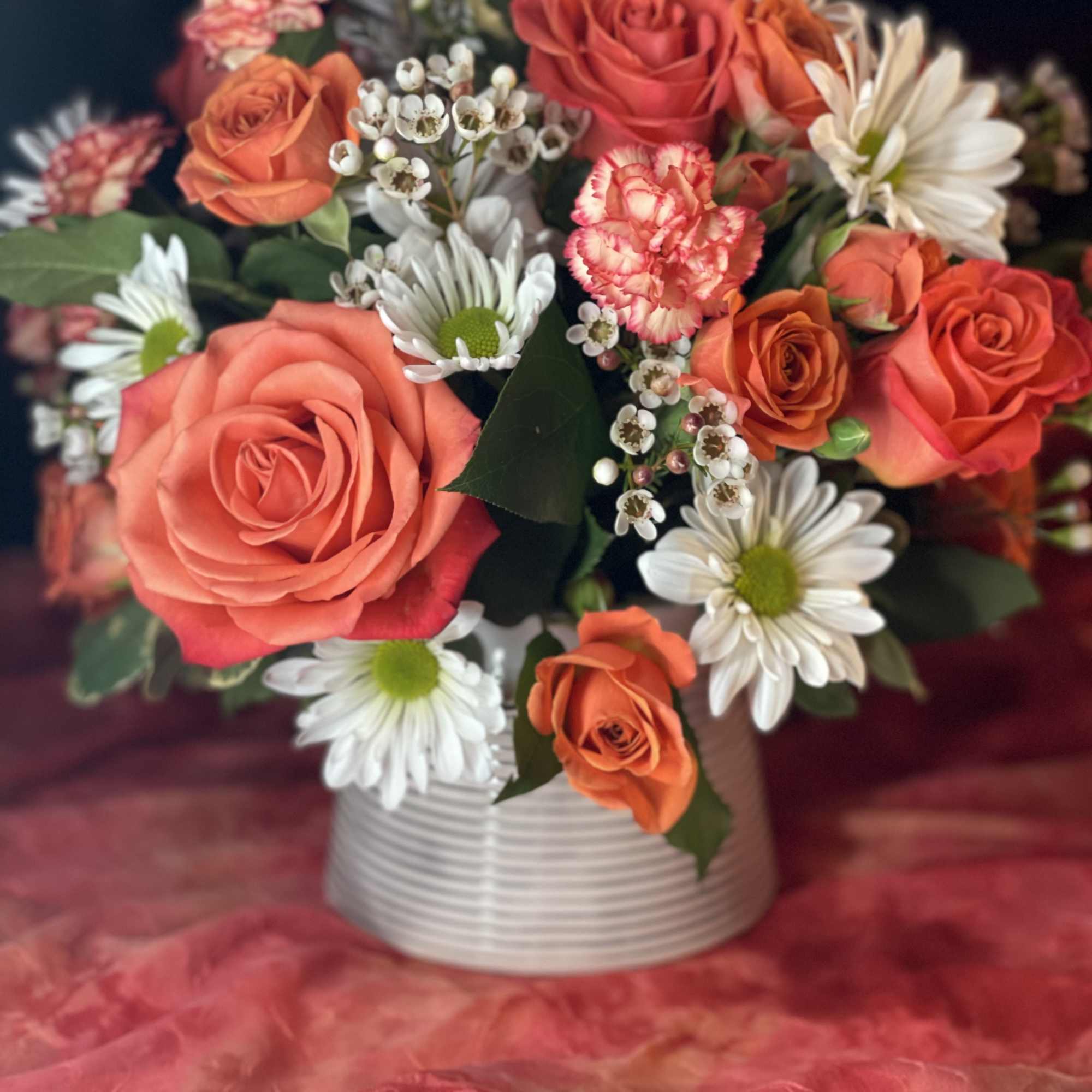 Bouquet of orange roses and white daisies in a white vase