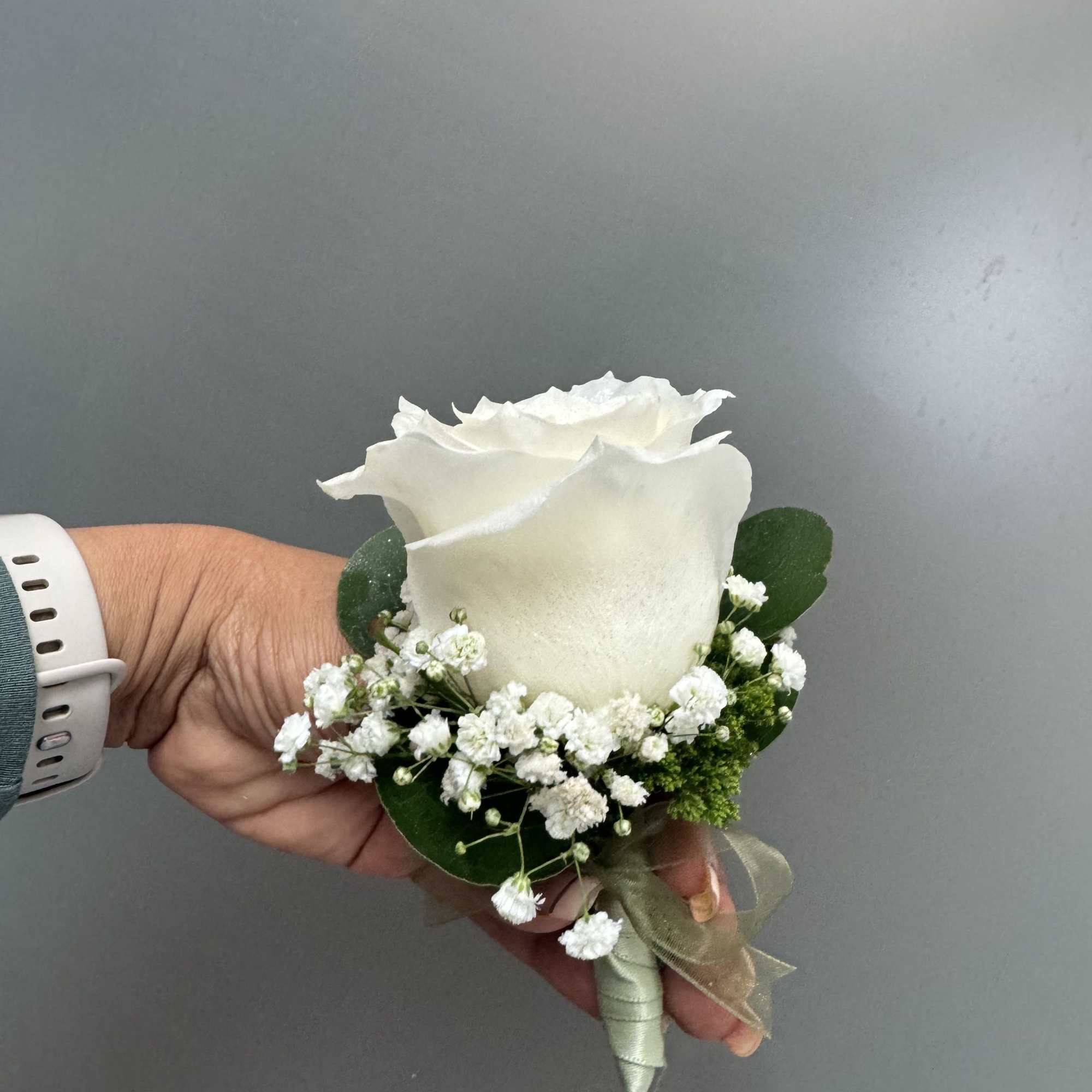 White rose boutonniere with baby's breath and green ribbon