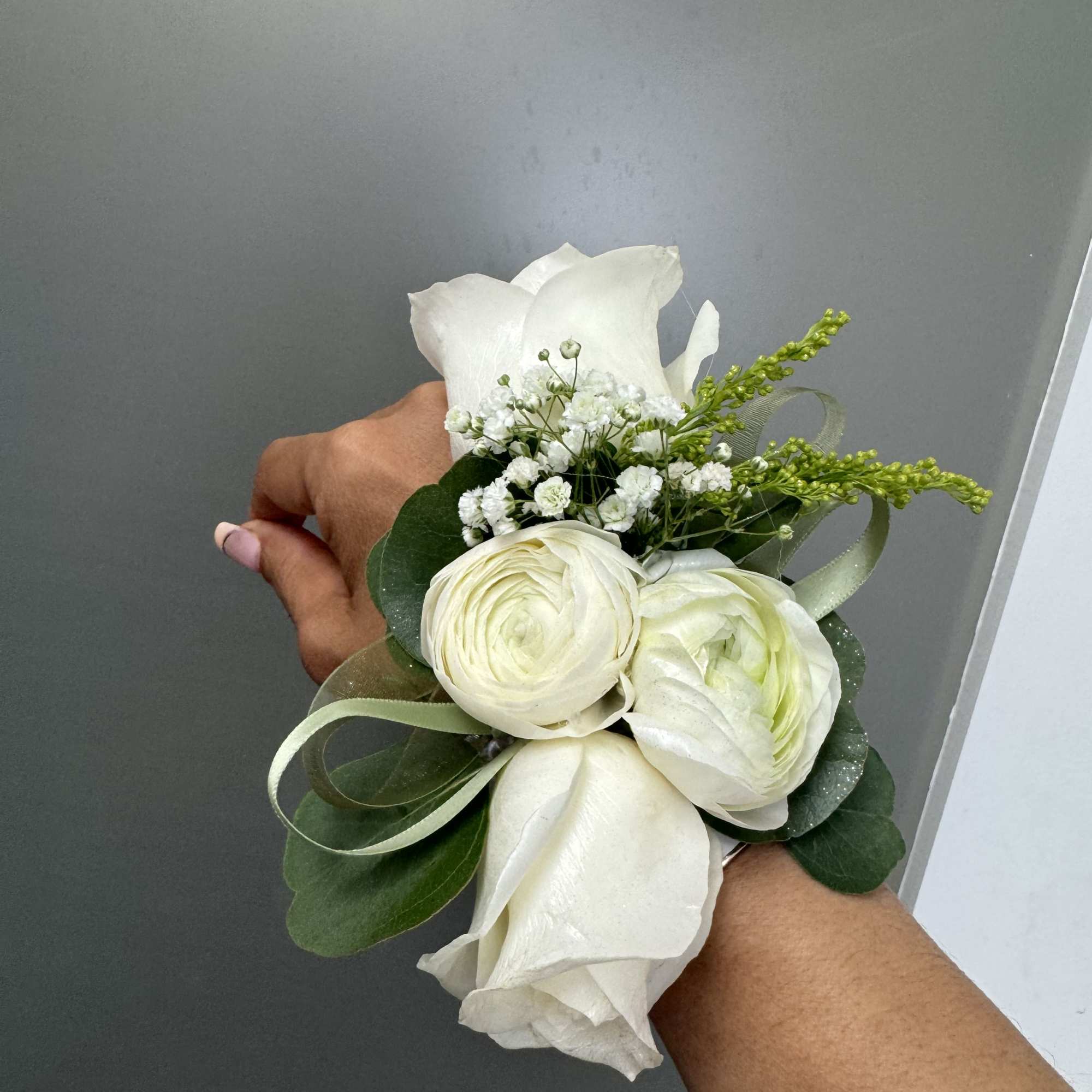 White rose corsage with small white filler flowers and ribbon