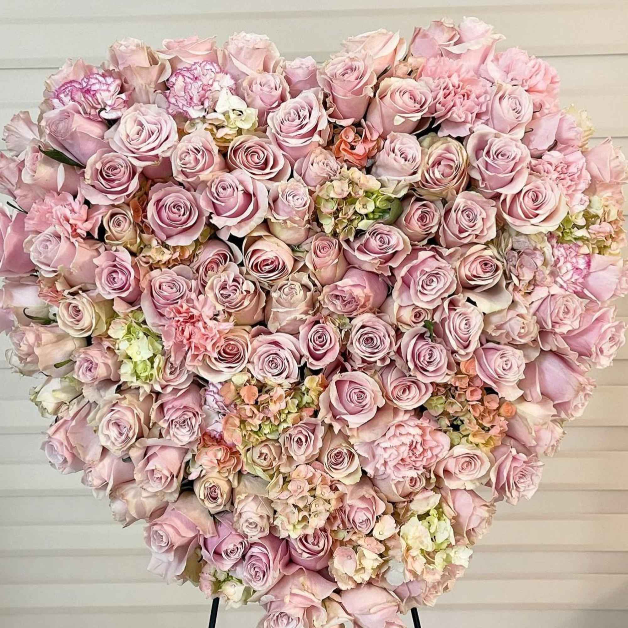 Heart-shaped arrangement of pink roses and carnations