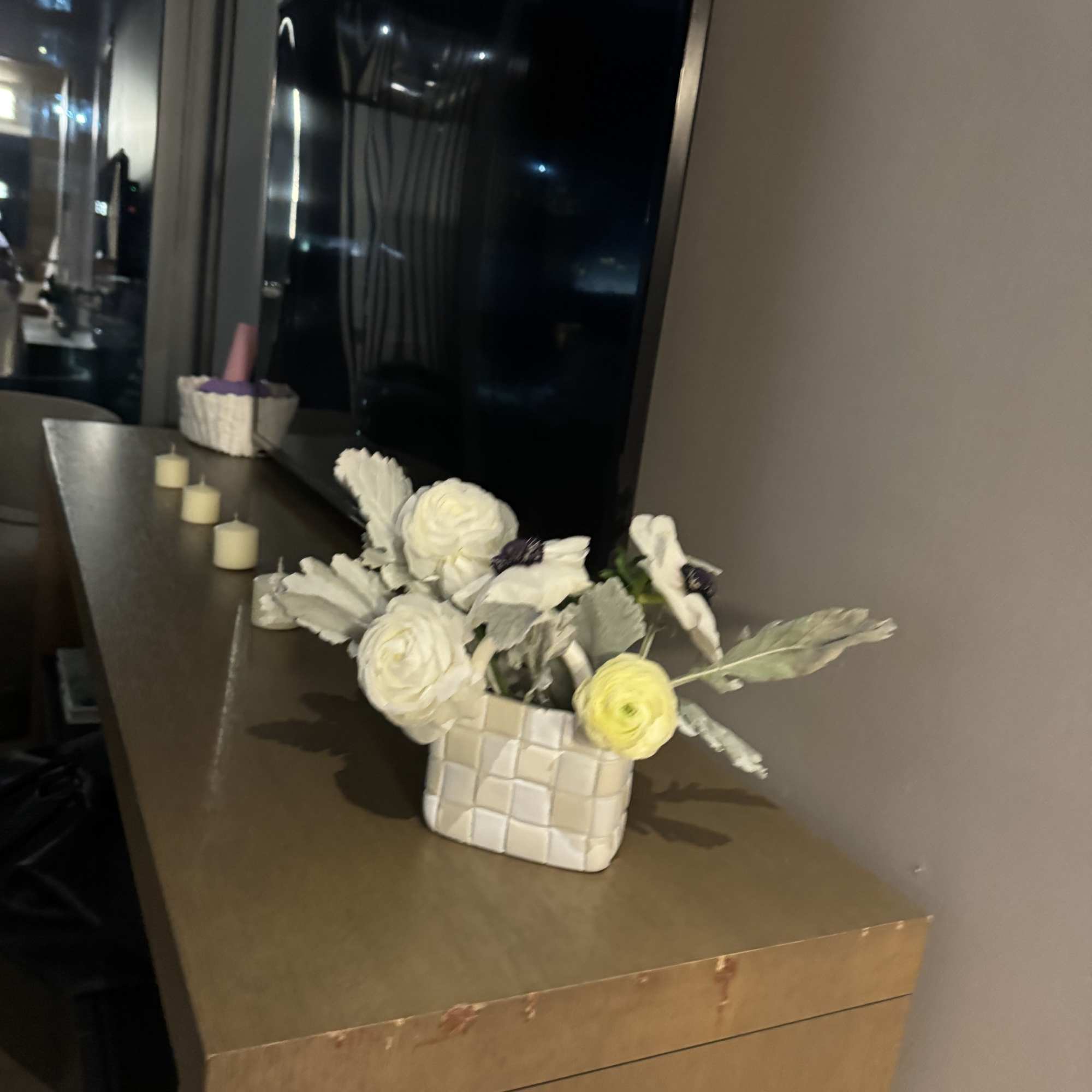 White and pale yellow flowers in a woven square vase