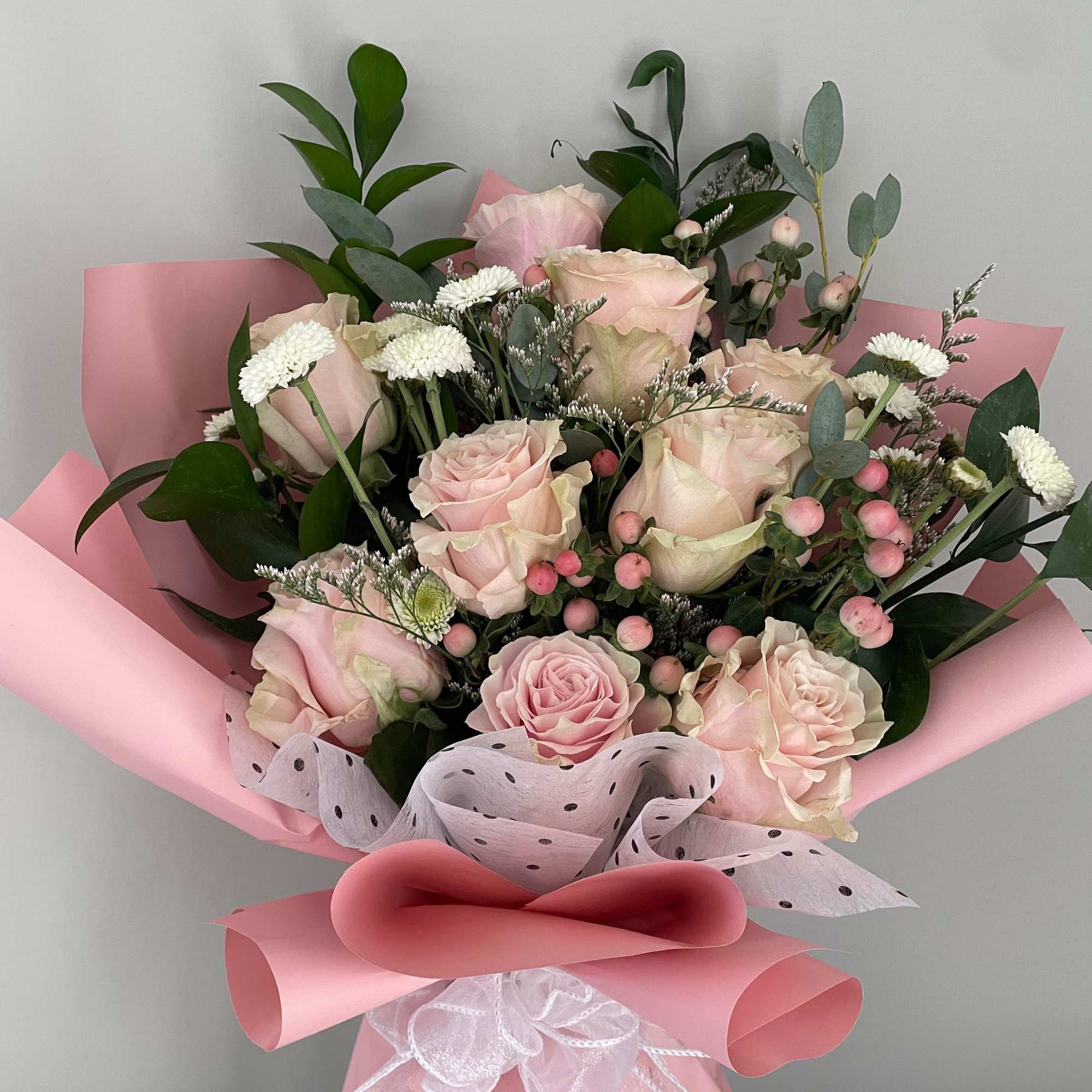 Bouquet of pale pink roses with white filler flowers in pink wrapping