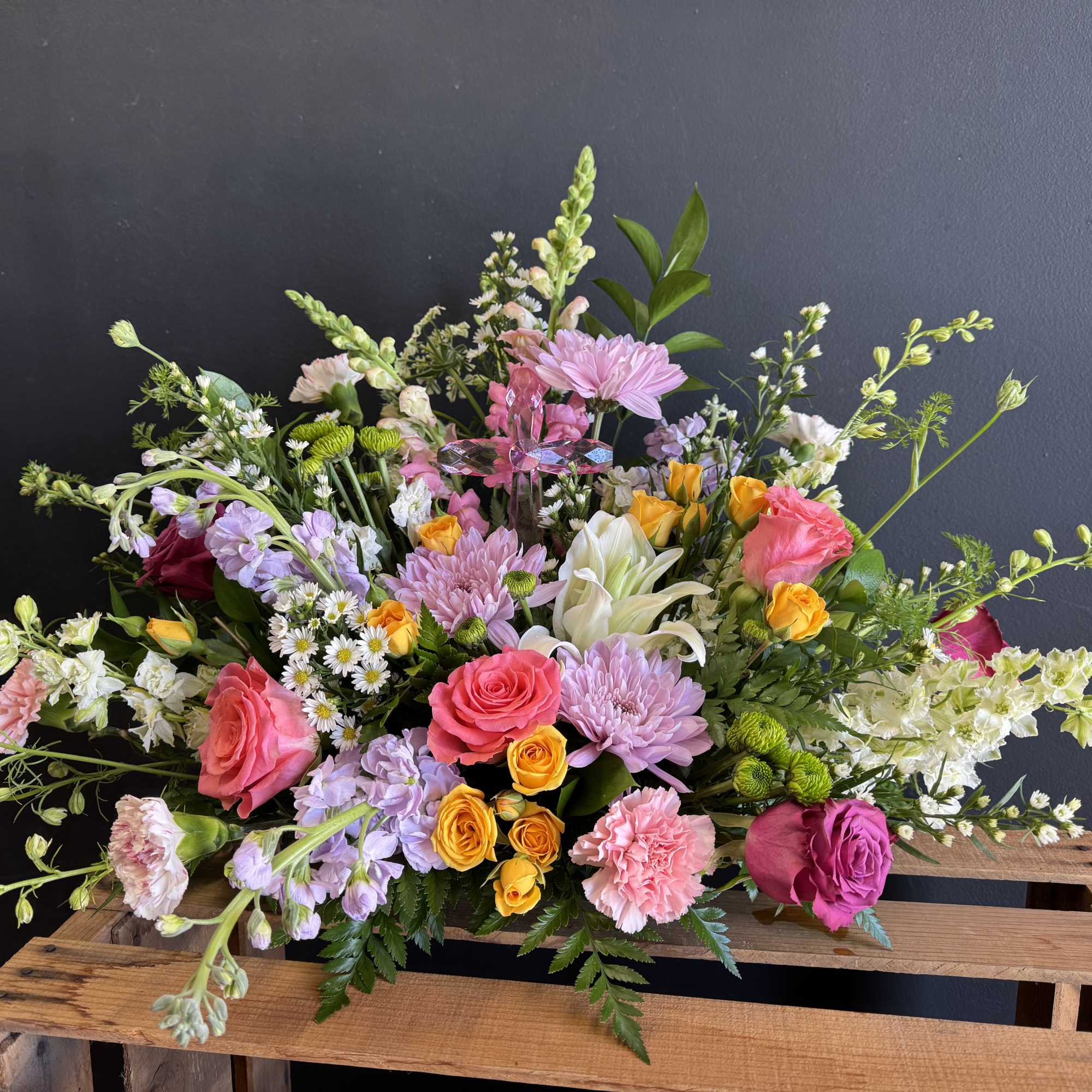 A lush garden-style arrangement featuring pink roses, lilies, snapdragons, carnations, and whimsical