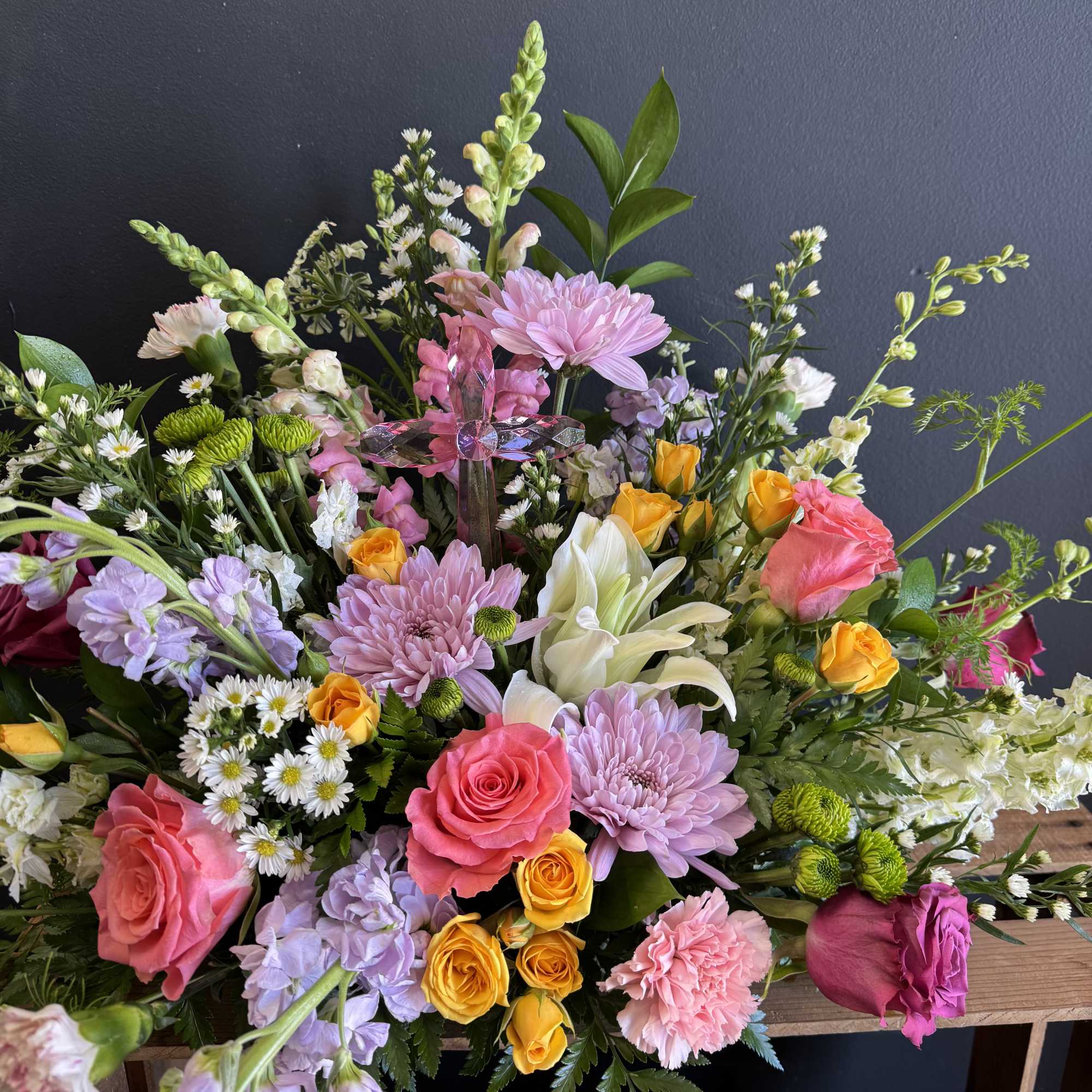 A lush garden-style arrangement featuring pink roses, lilies, snapdragons, carnations, and whimsical