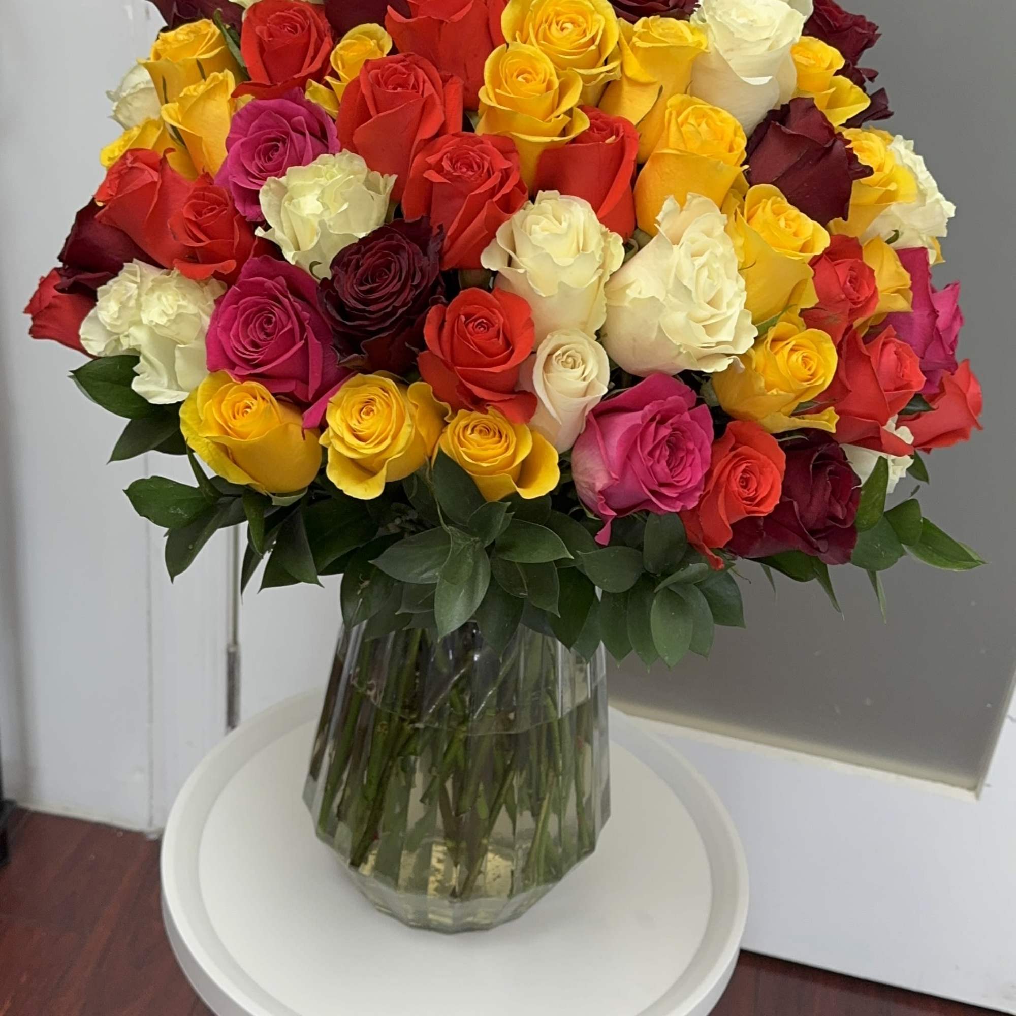 Large bouquet of multicolored roses in a clear glass vase