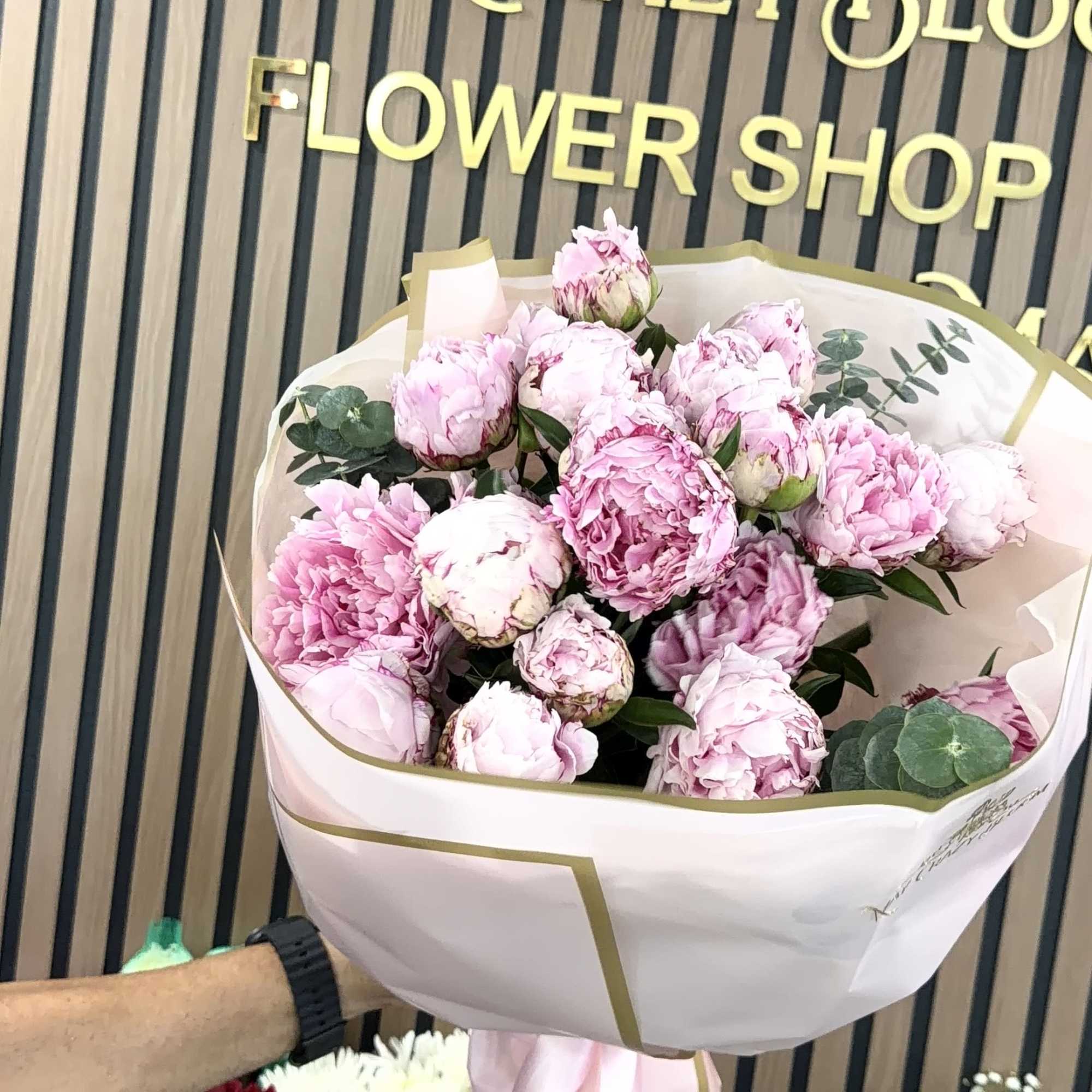 A lush cluster of blush and soft pink peonies creates an immediate