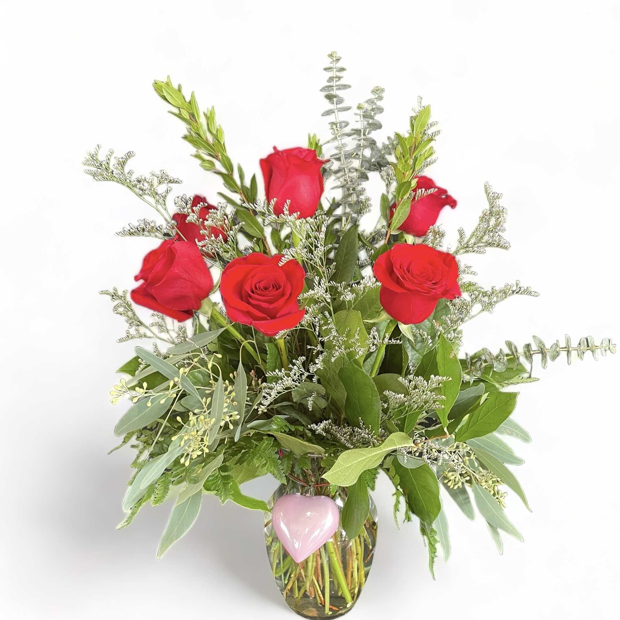Red roses in a glass vase with a pink heart charm