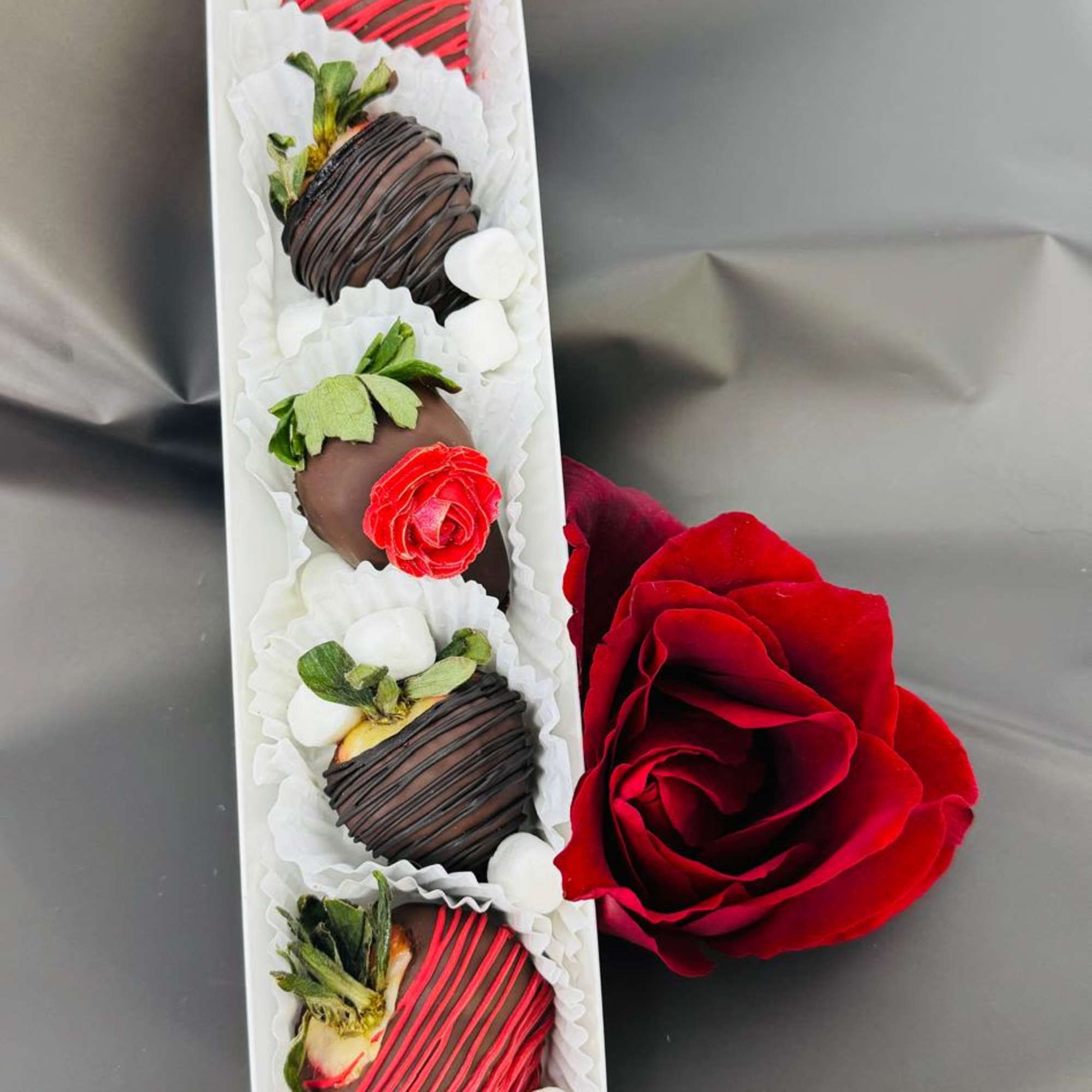 Box of chocolate-covered strawberries with a red rose