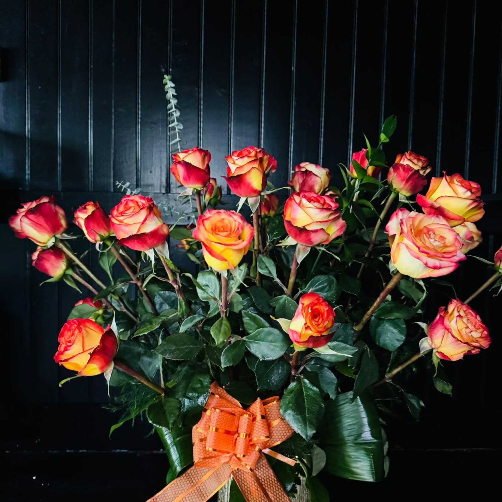 Bouquet of red and yellow roses with an orange ribbon