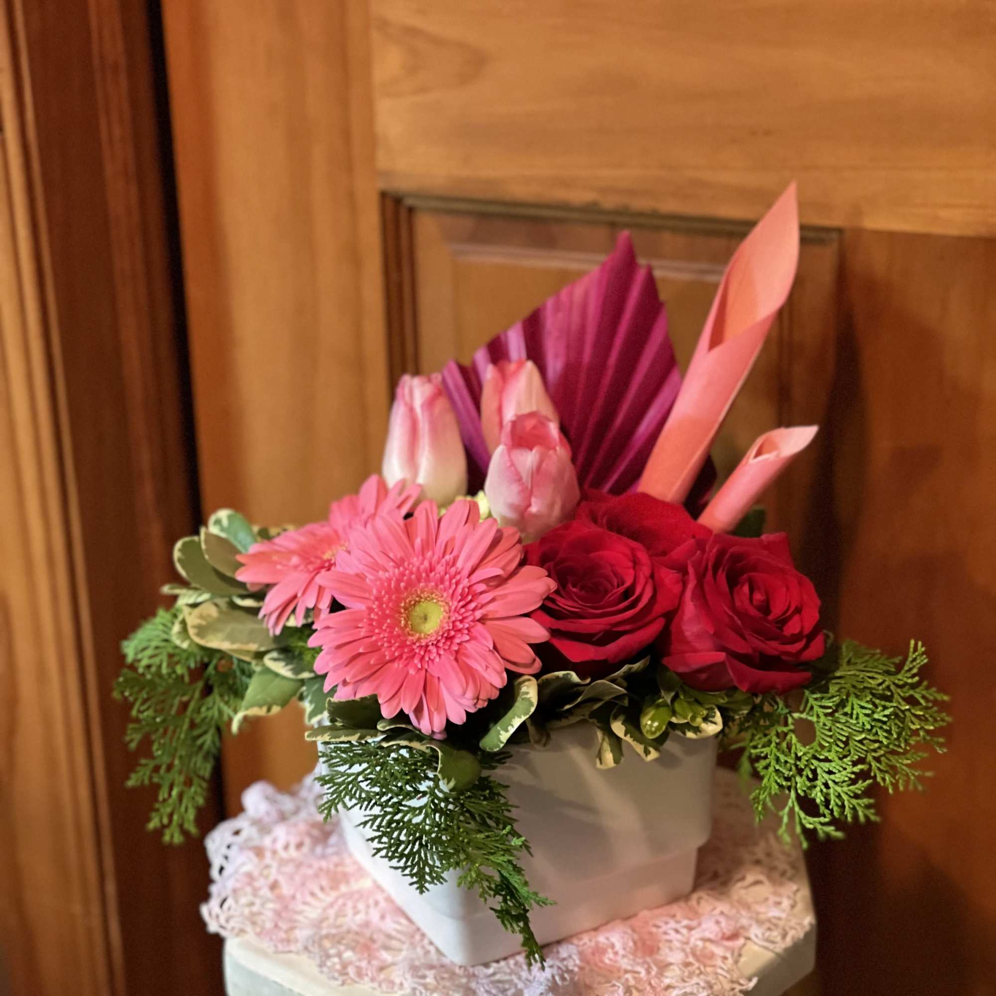 Pink gerbera daisies and red roses arranged in a white box
