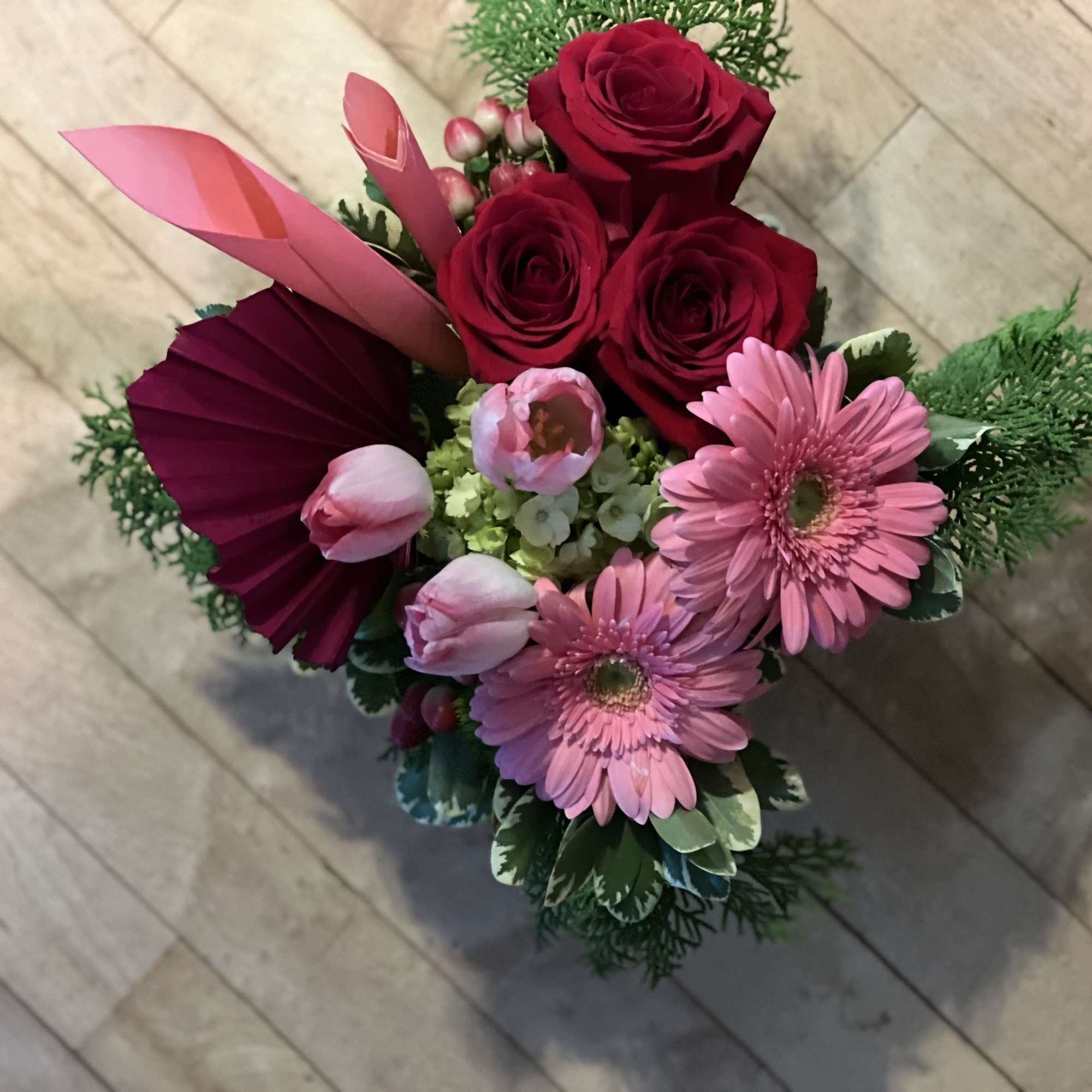 Bouquet of red roses and pink gerbera daisies with folded pink paper accents